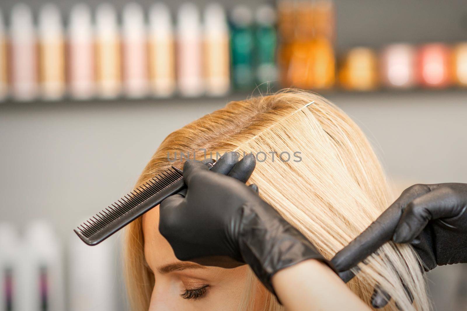 Hairdresser's hand combs female hair before dyeing in a beauty salon