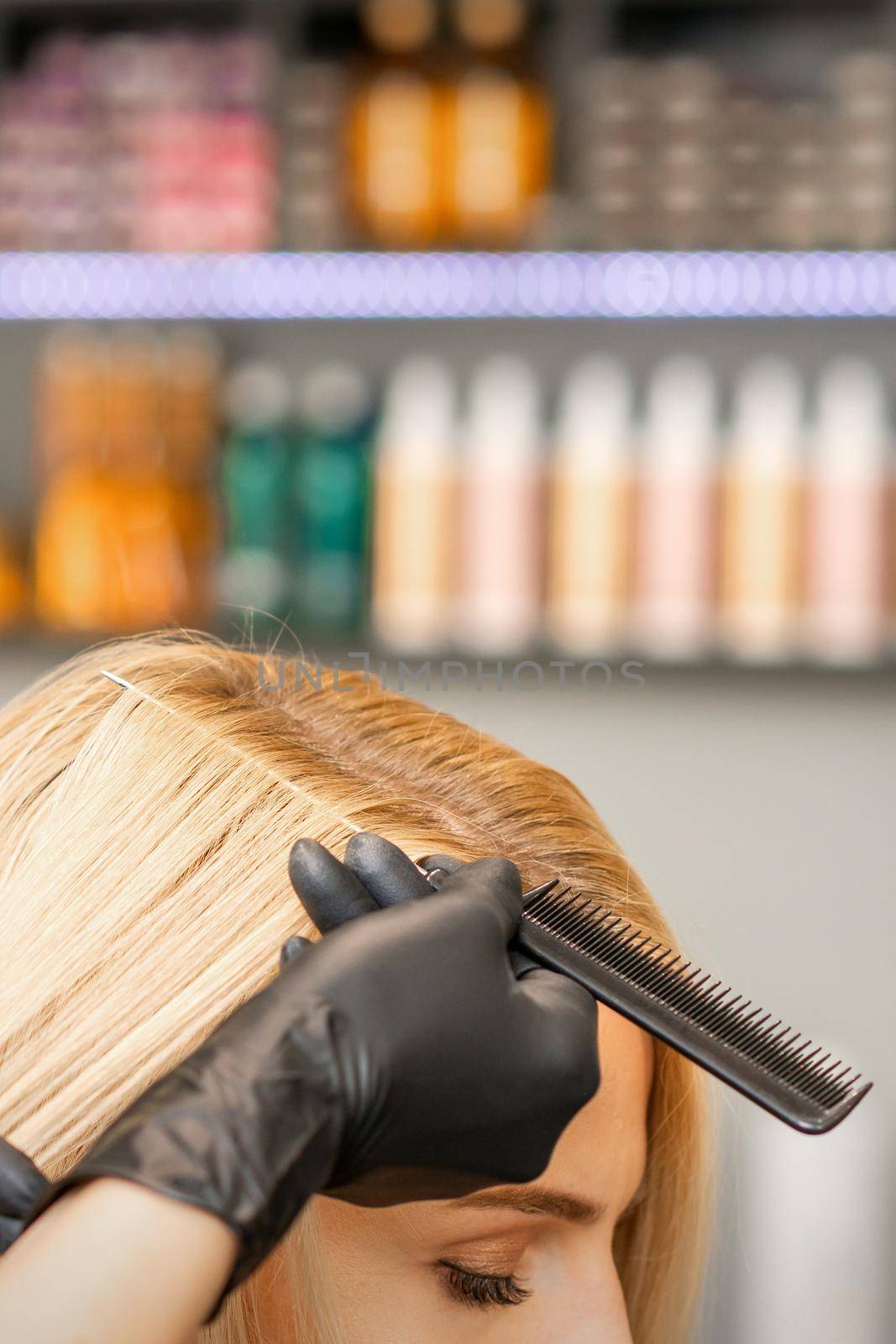 Hairdresser's hand combs female hair before dyeing in a beauty salon