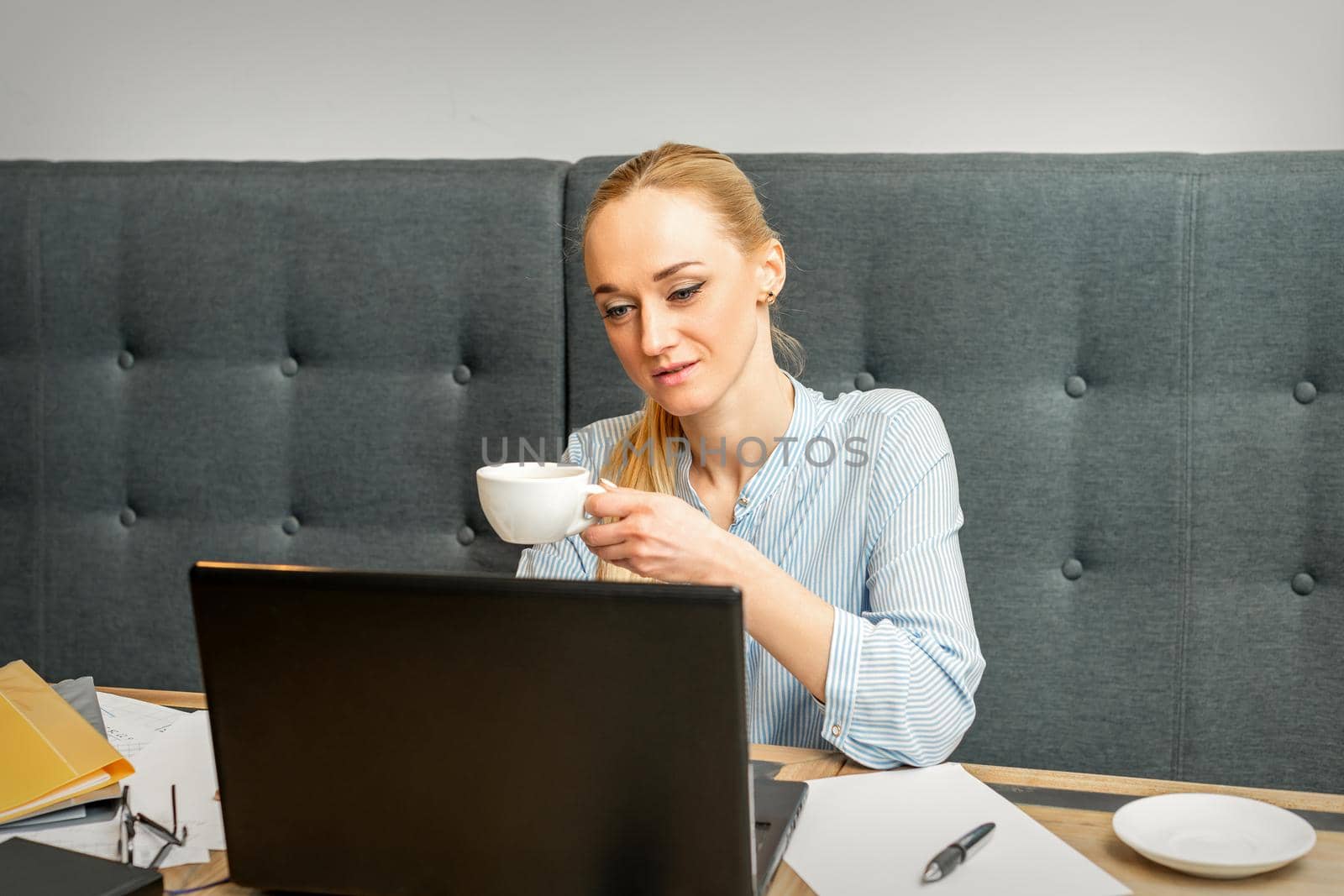 Portrait of a young businesswoman using laptop sitting at the table with a cup of coffee in a cafe