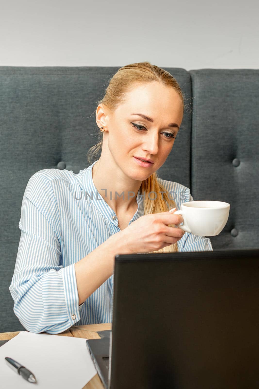 Portrait of a young businesswoman using laptop sitting at the table with a cup of coffee in a cafe