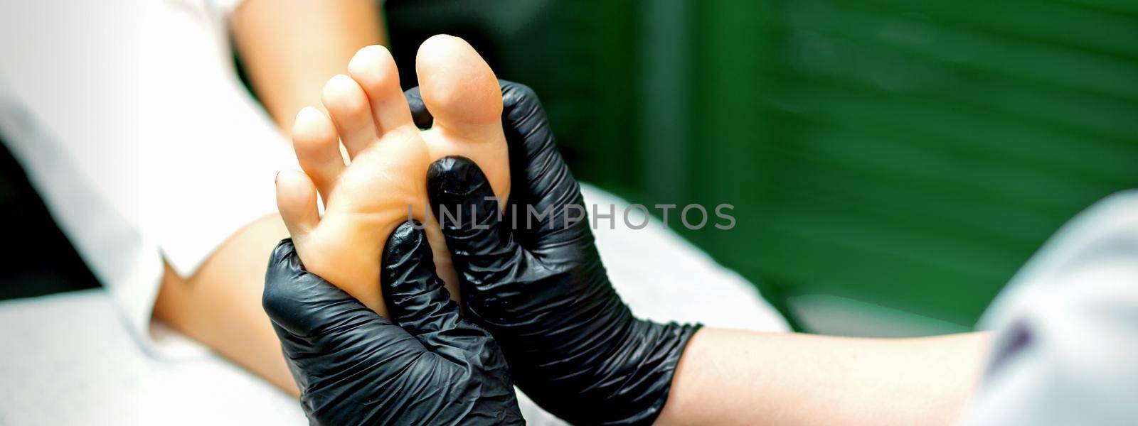 Young woman receiving foot massage by hands of beautician in spa beauty salon