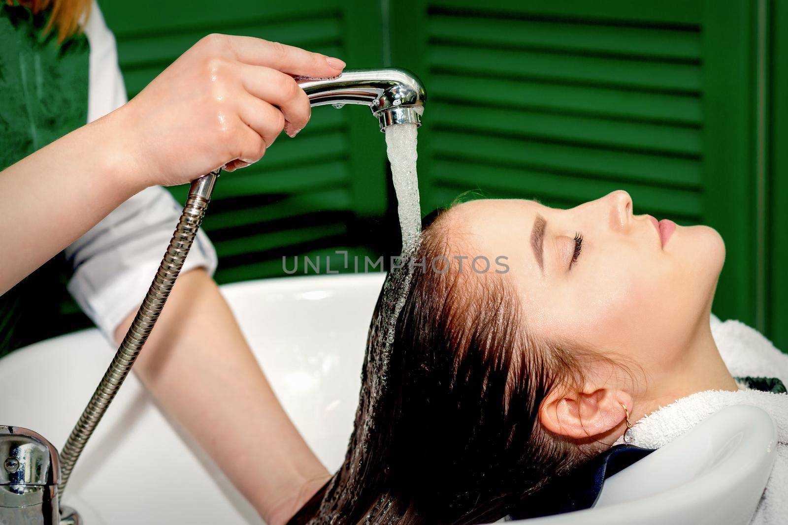 Side view photo of a young caucasian woman receiving washing hair in a hair salon