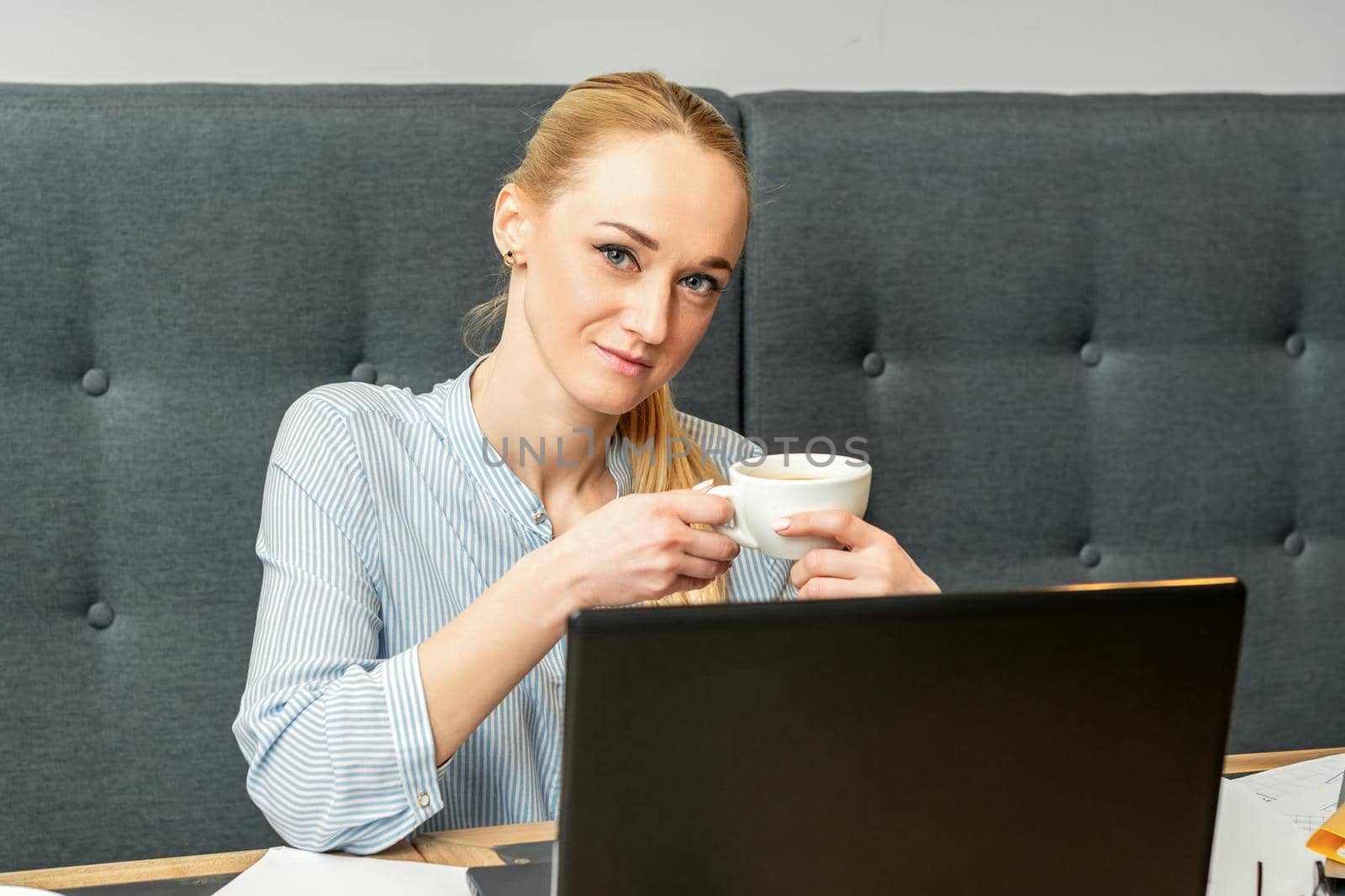 Portrait of a young businesswoman using laptop sitting at the table with a cup of coffee in a cafe