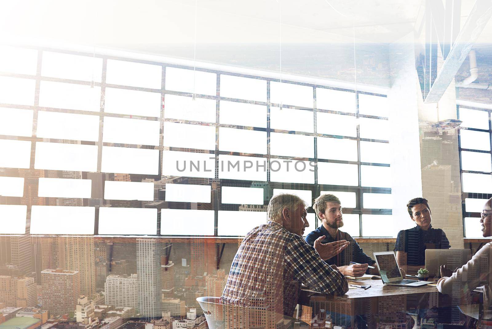 Working hard to become the best in the city. Multiple exposure shot of businesspeople having a meeting superimposed over a cityscape