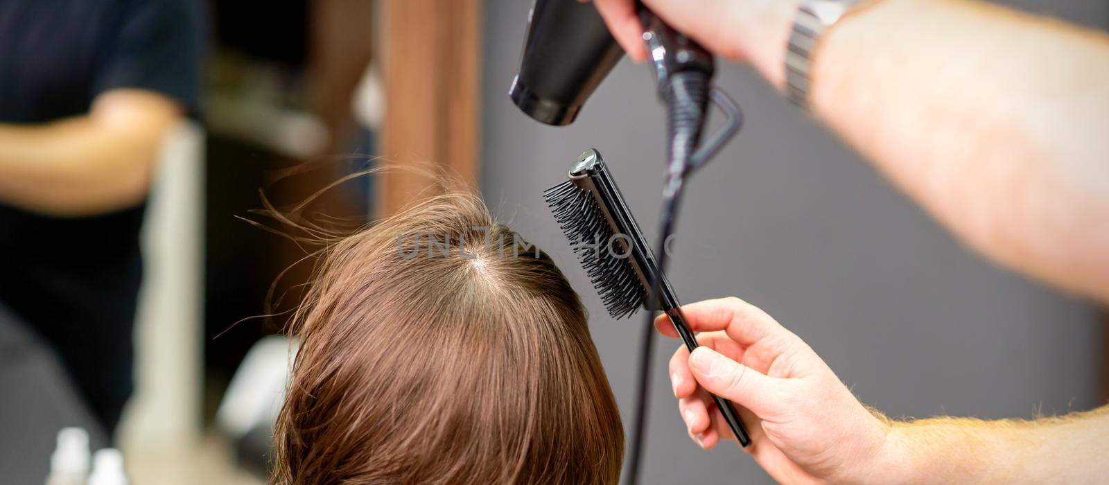 Hairdresser dries brown hair of woman by okskukuruza