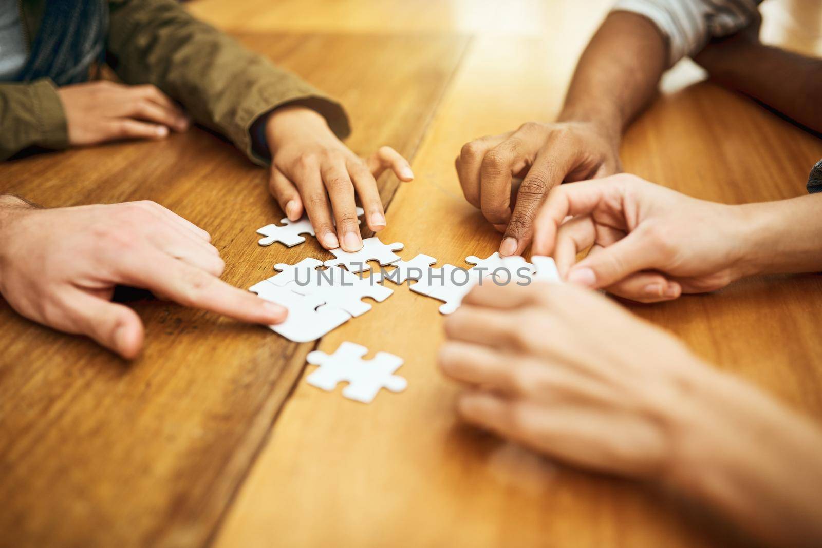 Teamwork gets the job done. High angle shot of a group of unrecognizable university students building a puzzle while studying in the library