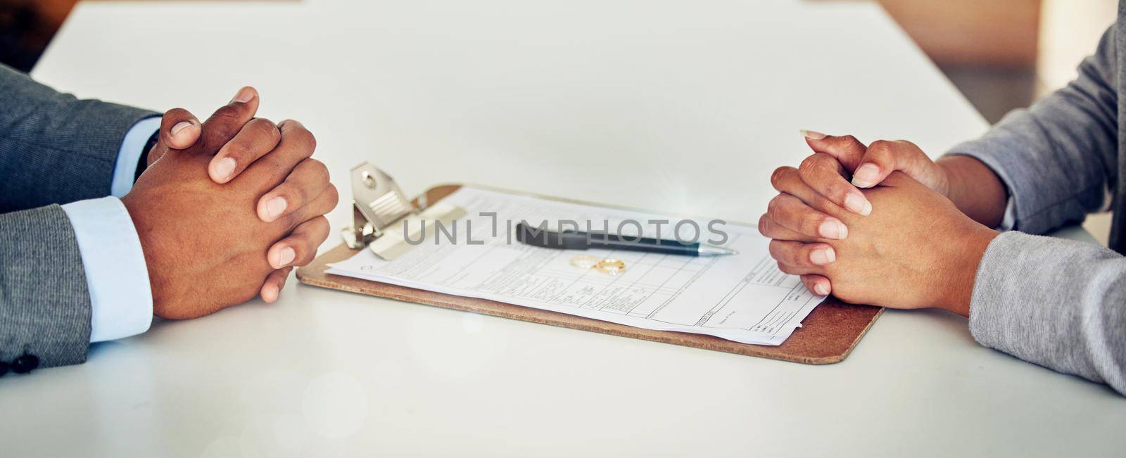 Couple hand sign legal divorce documents, contract or paper deal in a lawyer office with ring placed on table. Woman and man with signature on marriage paperwork after agreement at family law office.