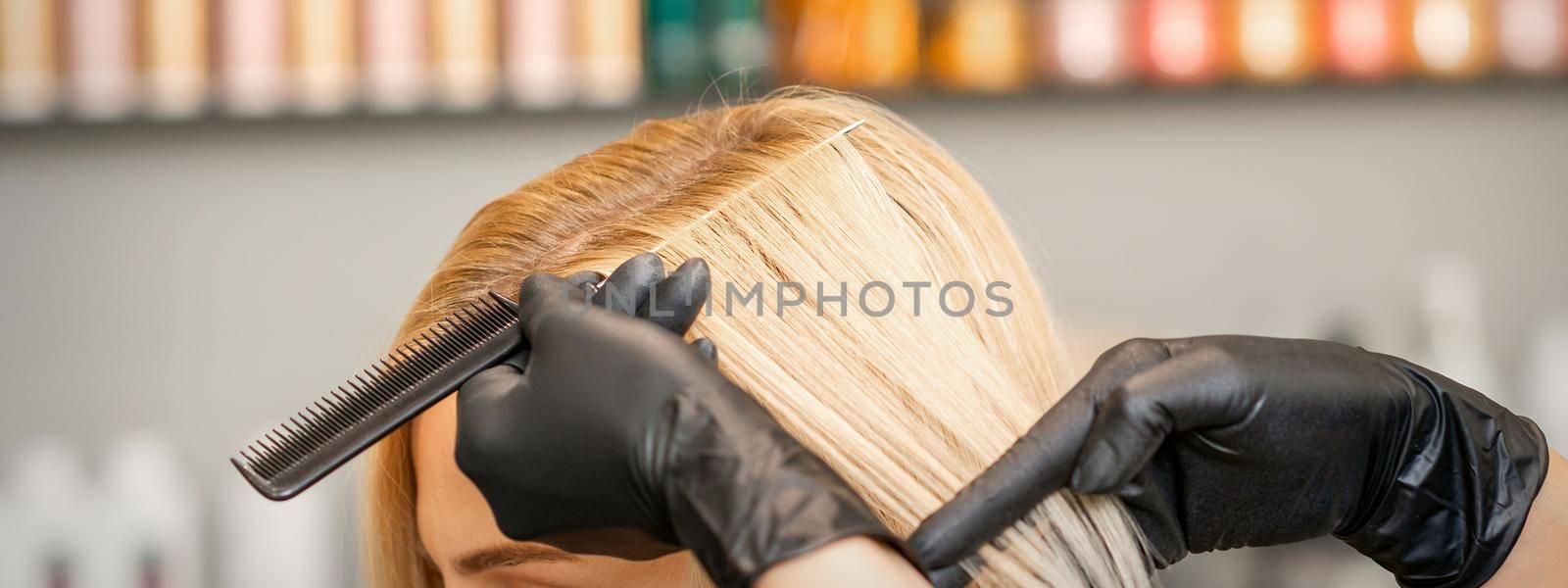 Hairdresser's hand combs female hair before dyeing in a beauty salon