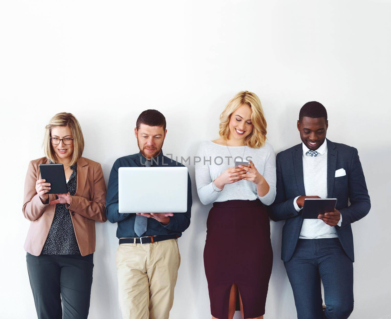 The internet makes marketing a breeze. a group of entrepreneurs using wireless devices against a white background. by YuriArcurs