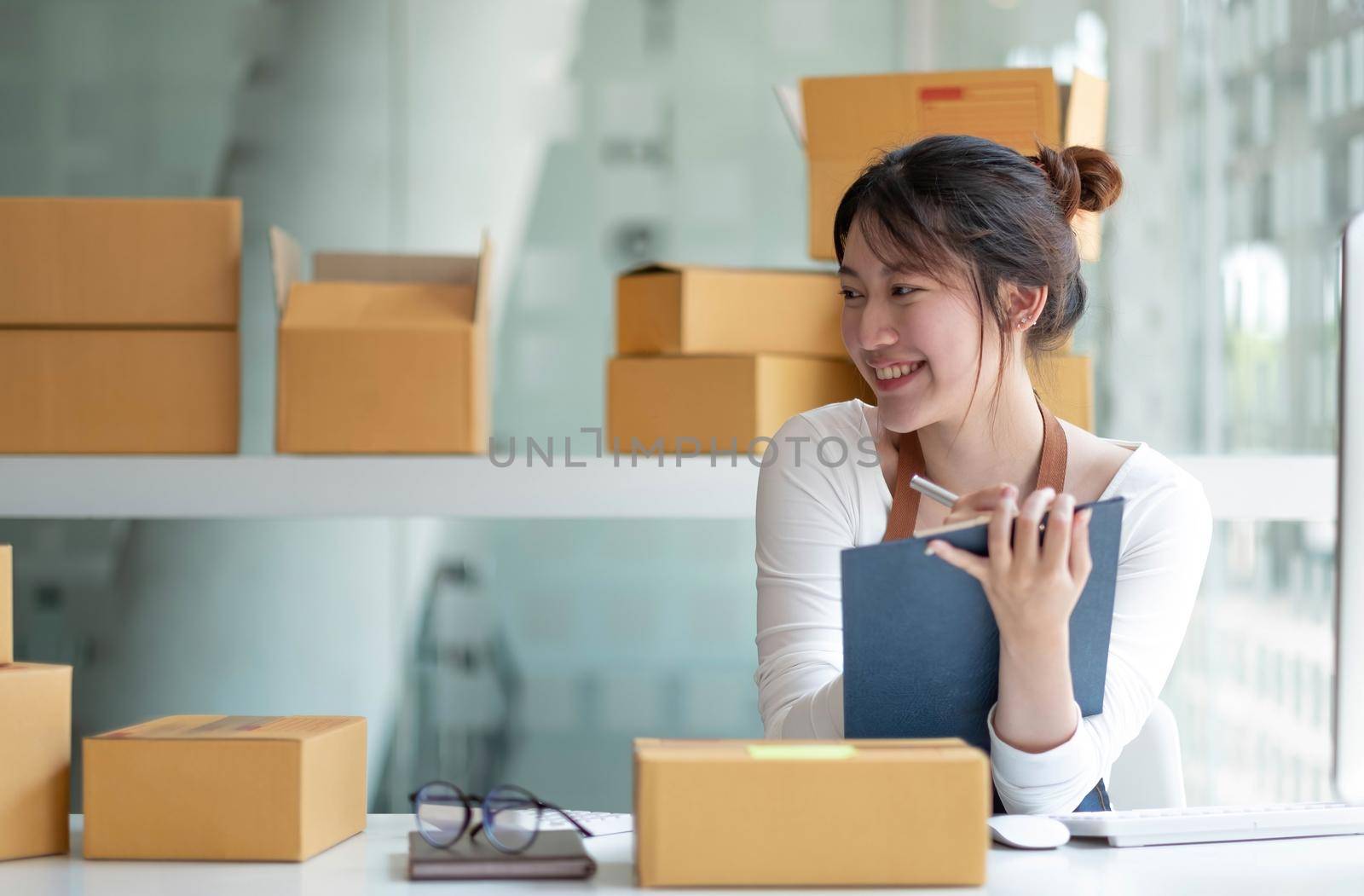 Starting small businesses SME owners female entrepreneurs Use a laptop or notebook to receive and review orders online to prepare to pack boxes, sell to customers, SME online business ideas. by wichayada
