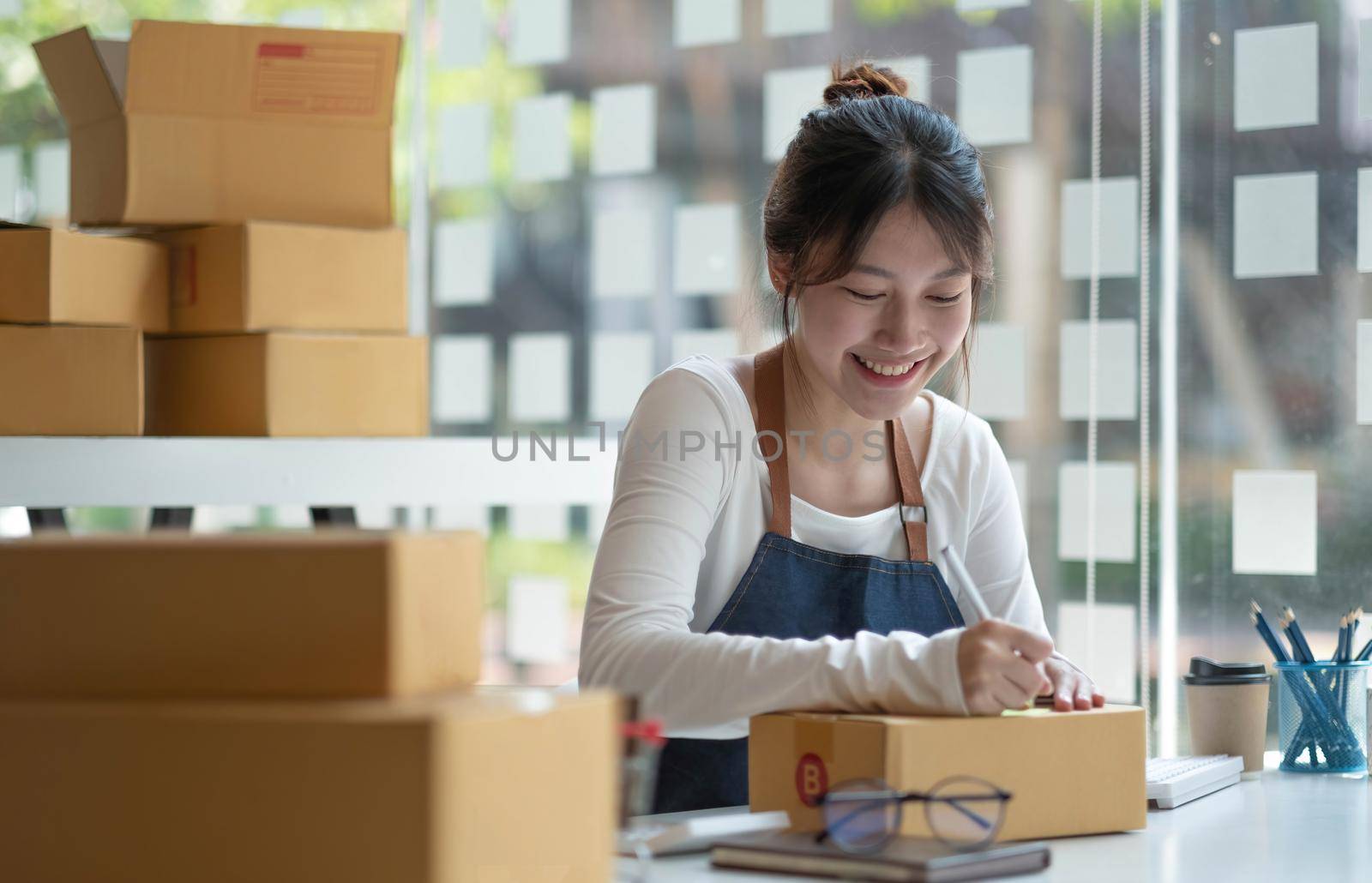 Asian female entrepreneurs and online sales. Woman is self-employed, working at home with a small business owner. Packaging delivery and SME online marketing.