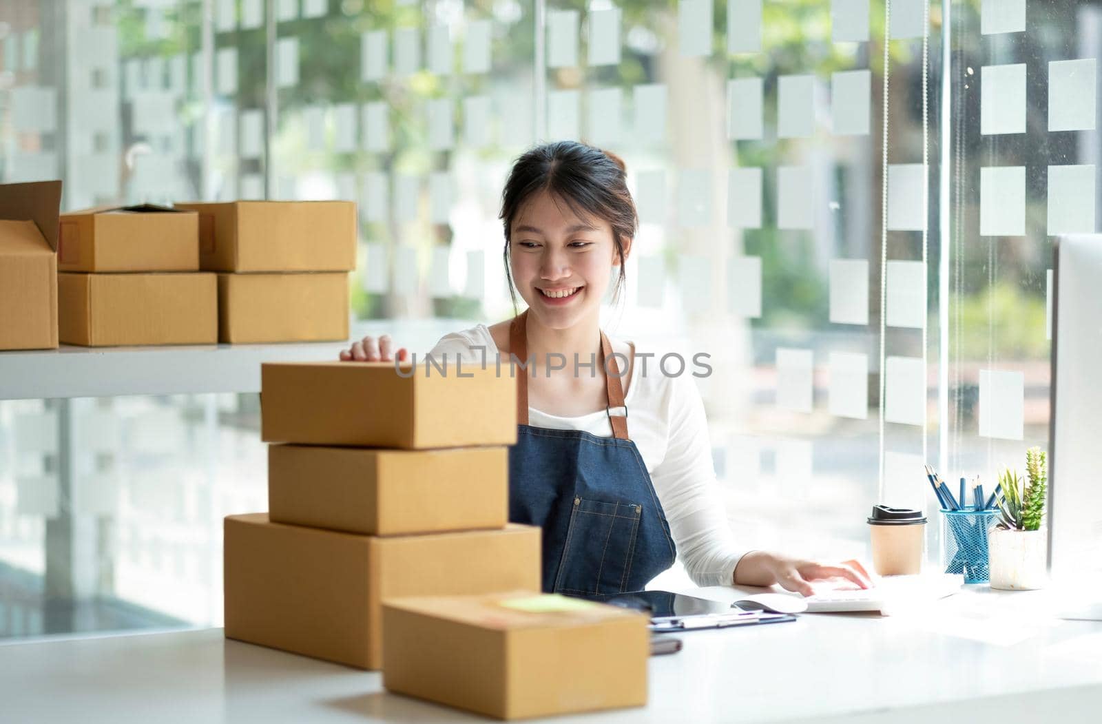 Startup SME small business entrepreneur SME or freelance Asian woman using a laptop with box, Young success Asian woman with her hand lift up, online marketing packaging box and delivery, SME concept. by wichayada