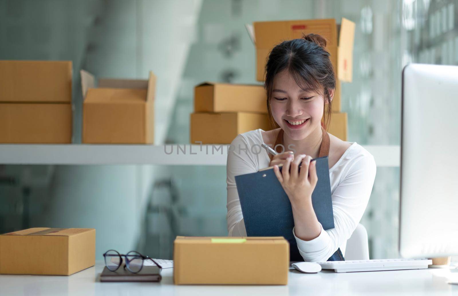 Starting small businesses SME owners female entrepreneurs Use a laptop or notebook to receive and review orders online to prepare to pack boxes, sell to customers, SME online business ideas..