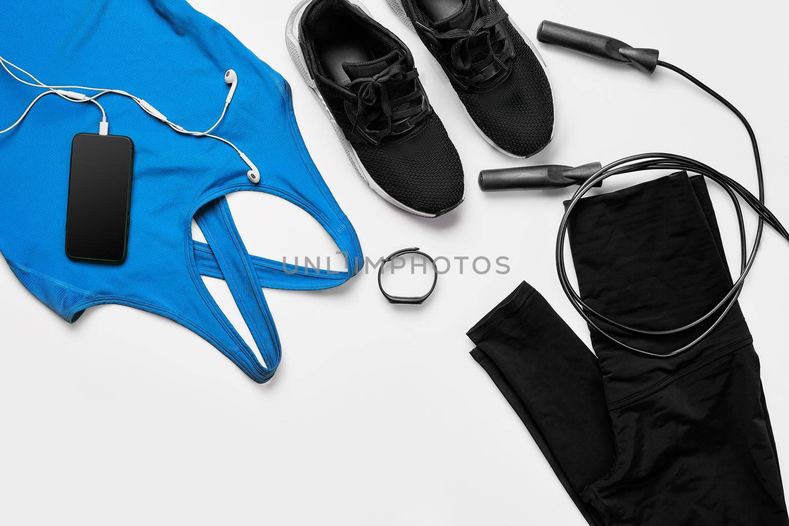 Sport, fitness, healthy lifestyle, cardio training and objects concept - close up of female sports clothing, skipping rope and bottle set on white background. Flat lay. Top view. Copy space