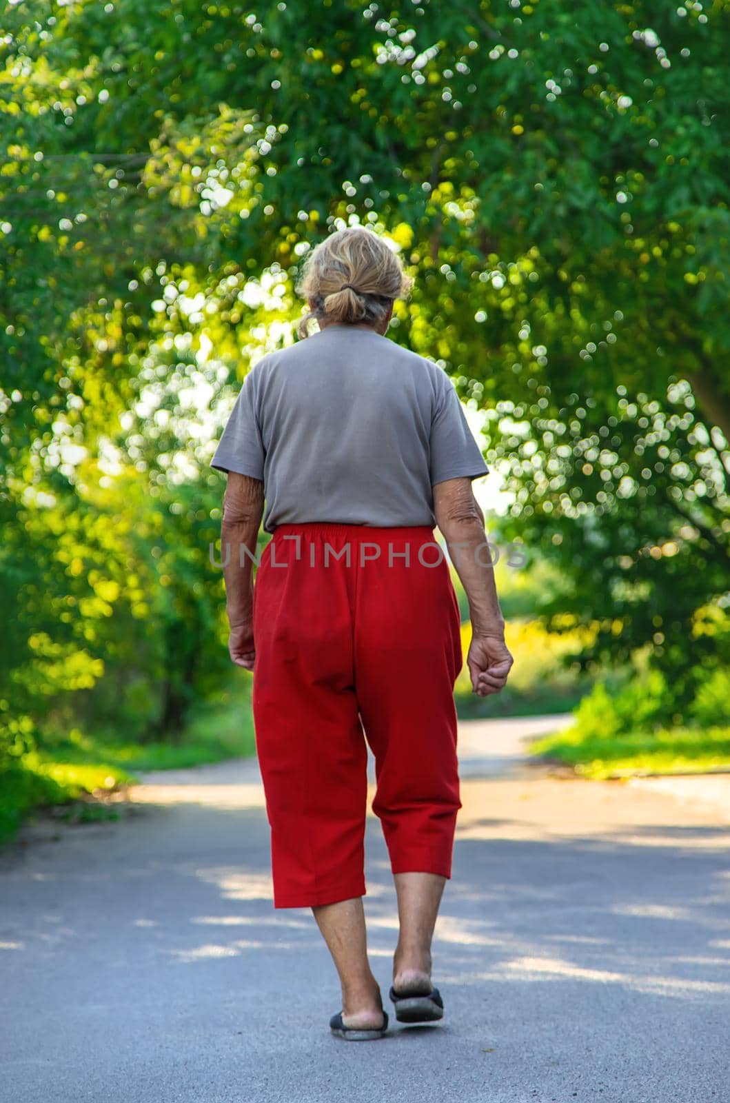 grandma is walking down the road. Selective focus. Nature.