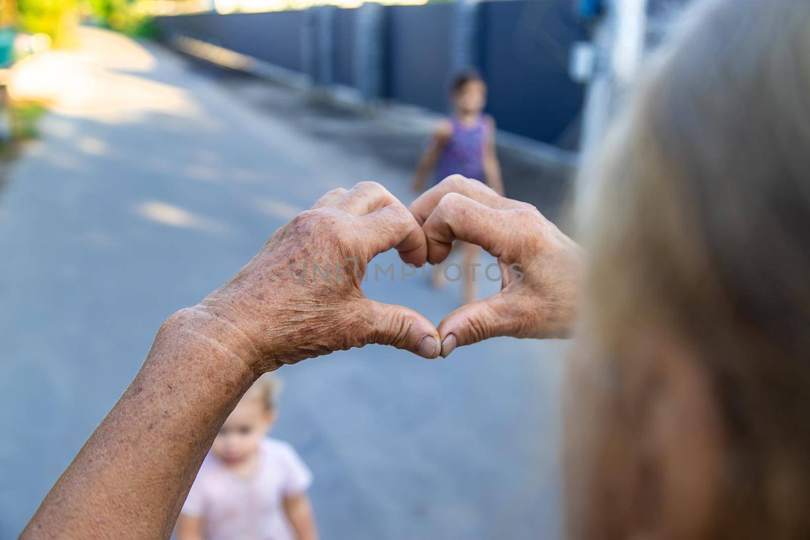 grandmother makes a heart with her hands. Selective focus. by yanadjana