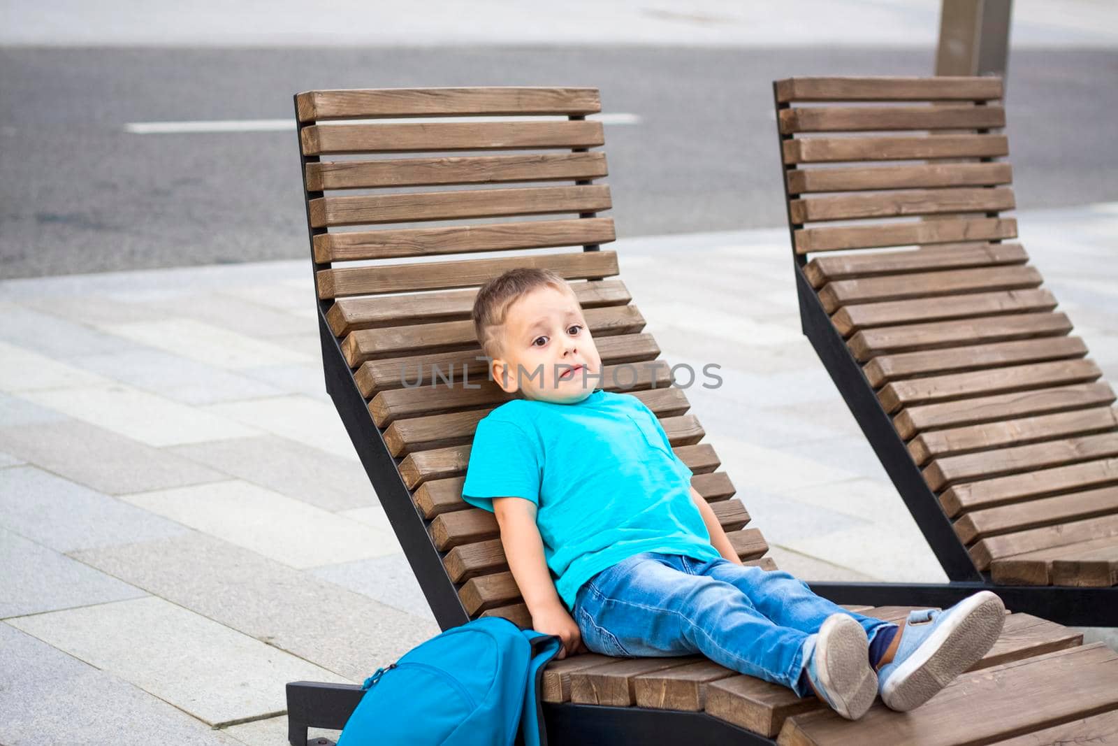 A boy in a blue T-shirt is resting on a chaise longue that stands on the embankment. Journey.  The face expresses natural joyful emotions. Not staged photos from nature.
