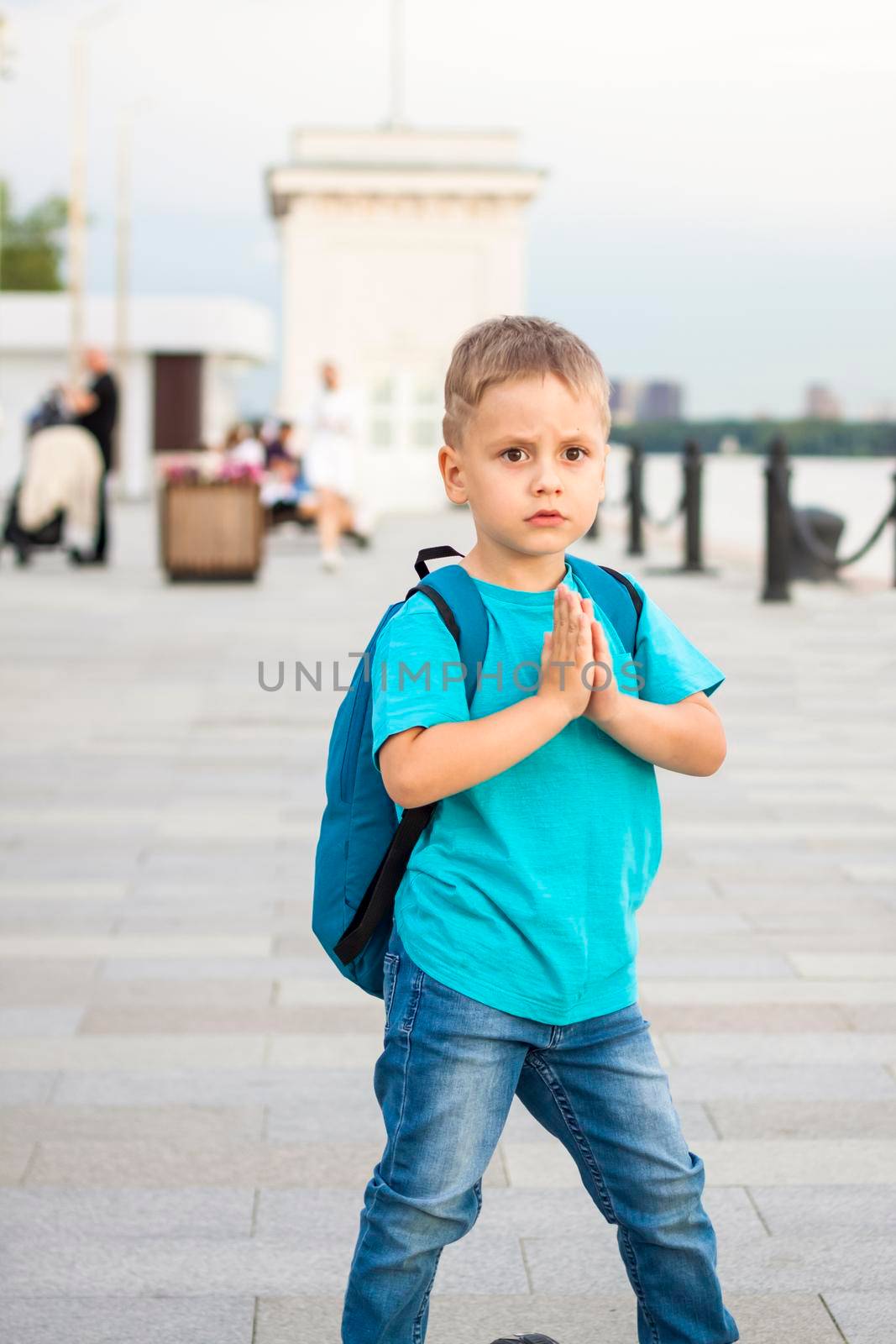 A boy on a scooter along the embankment of the city. Journey. Backpack on the back. The face expresses natural joyful emotions. Not staged photos from life.