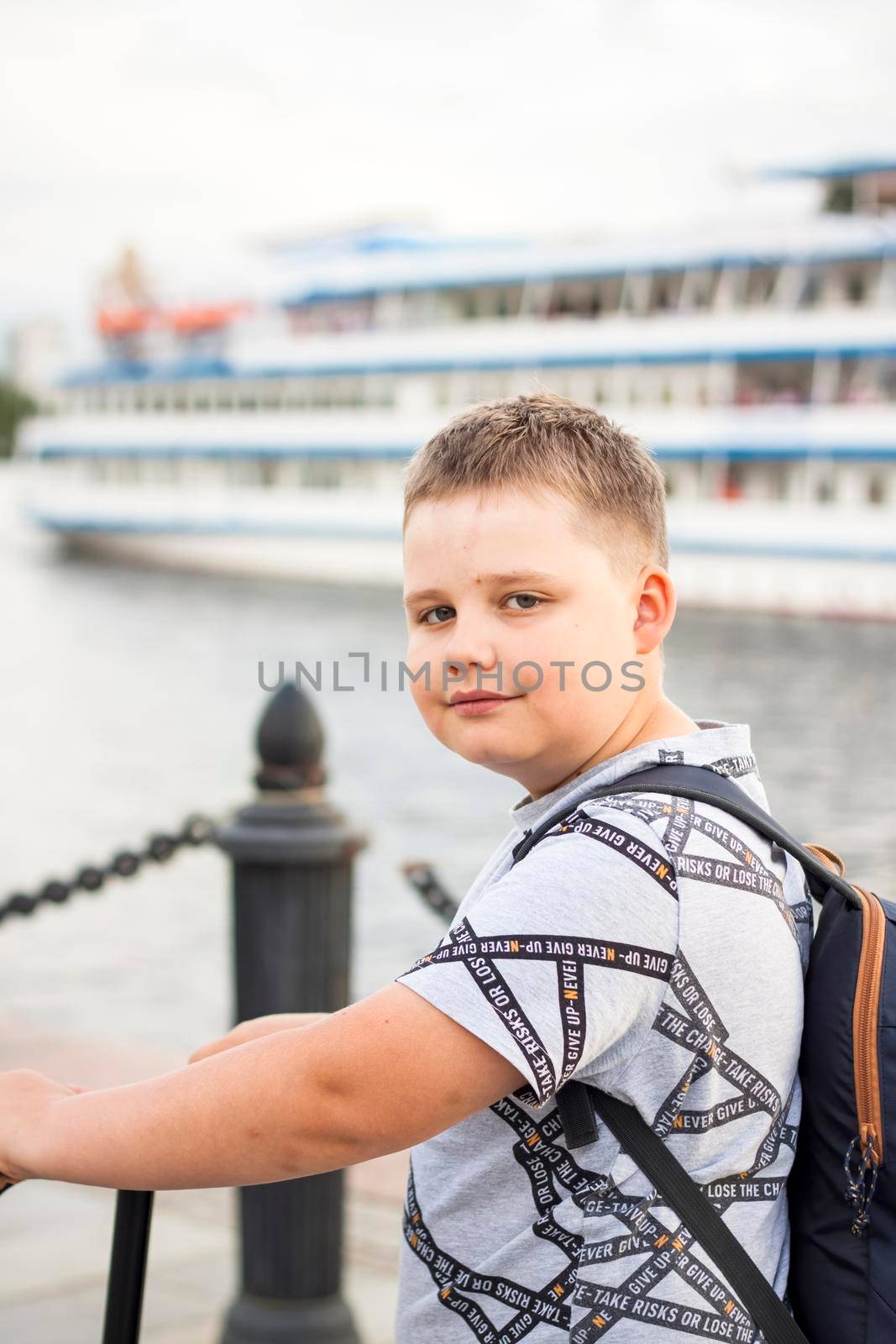 Portrait of a boy on the background of a river vessel. River station. Promenade