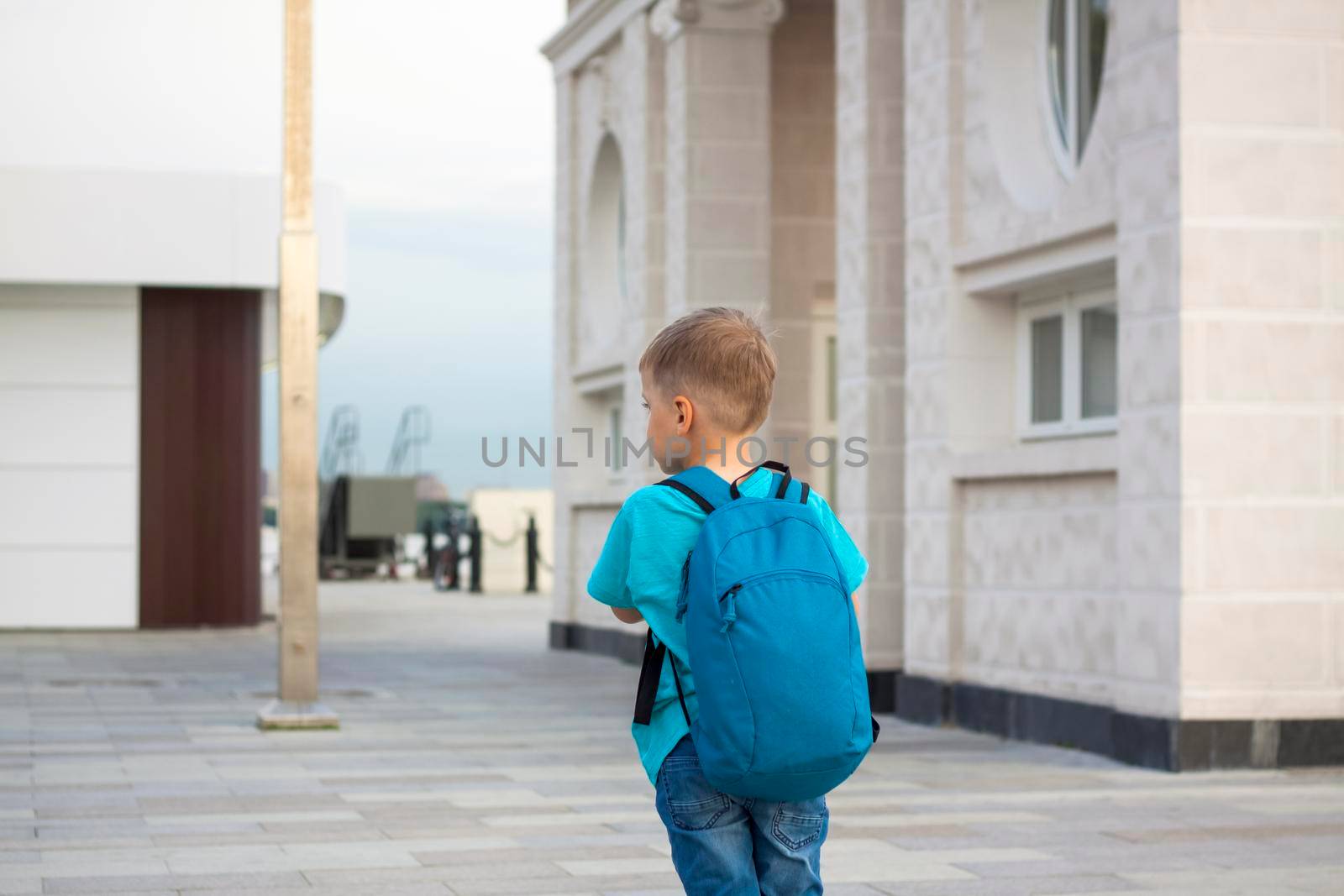 A boy on a scooter along the embankment of the city. Journey. Backpack on the back. The face expresses natural joyful emotions. Not staged photos from life.