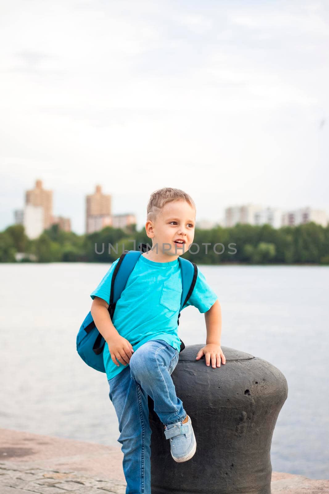 A boy in a blue T-shirt with a backpack on his back. Journey.  The face expresses natural joyful emotions. Not staged photos from nature.