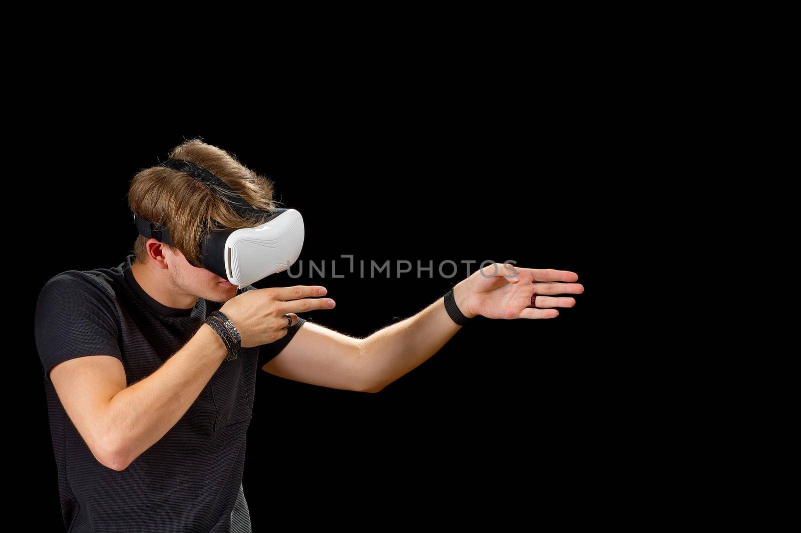 Young man wearing virtual reality VR glasses, goggles isolated on black background. Inside A Metaverse by PhotoTime