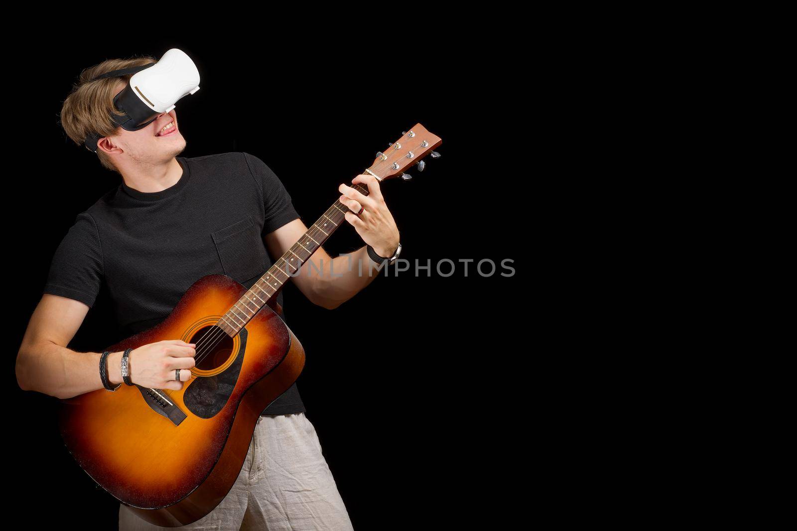 Man playing guitar game in virtual reality helmet. VR goggles, glasses, on black isolated background by PhotoTime