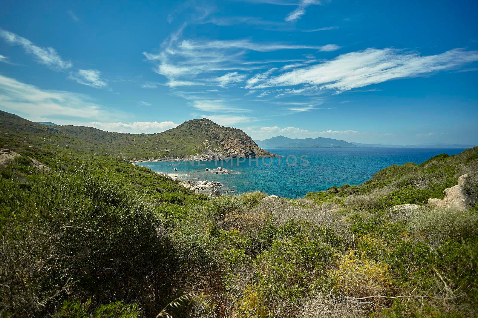 Panorama of a natural bay in the south of Sardinia in Italy with the mountains overlooking the sea in broad daylight during the summer.