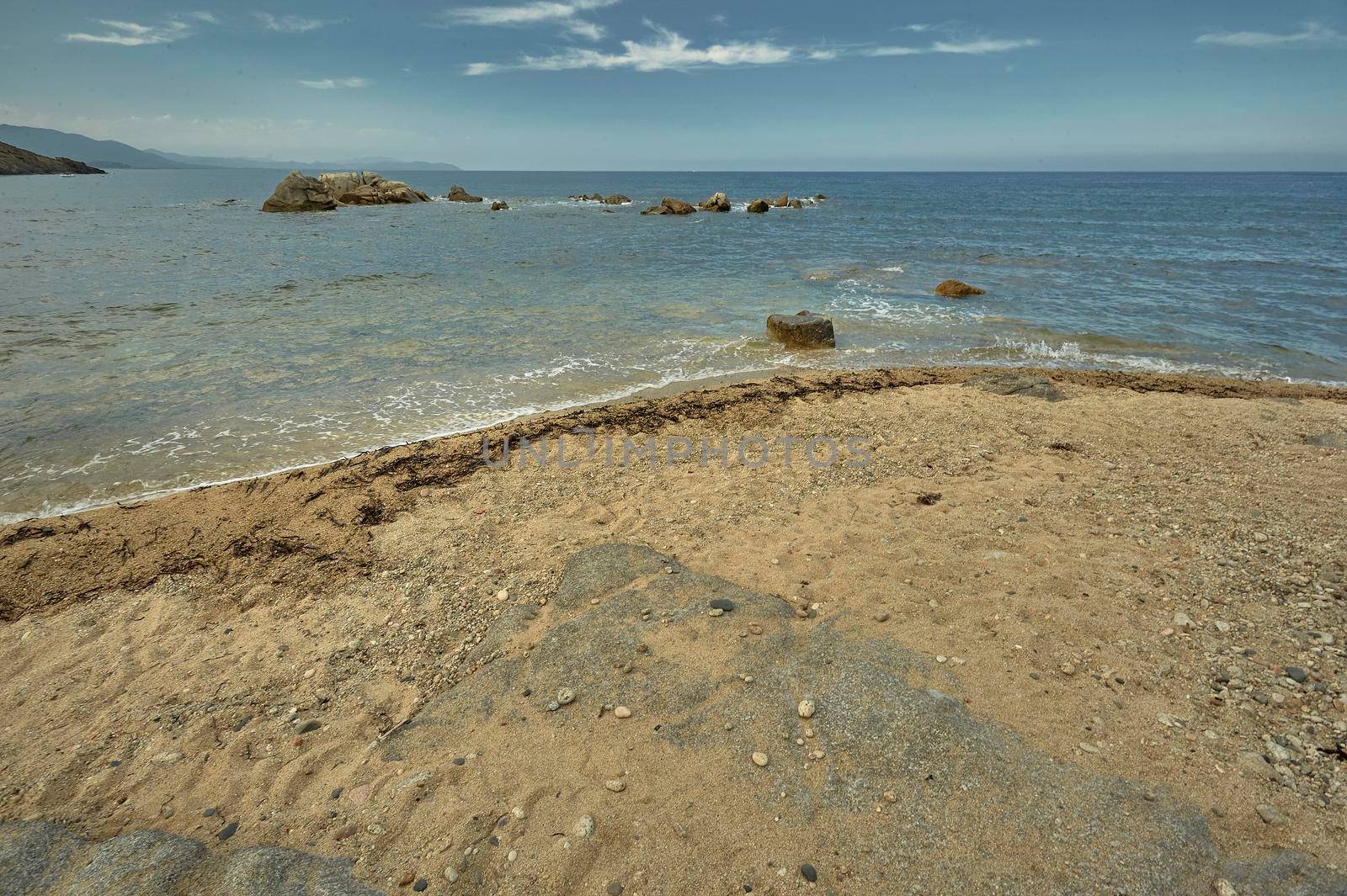 Detail of a portion of sandy beach overlooking the sea with the rocks inside.