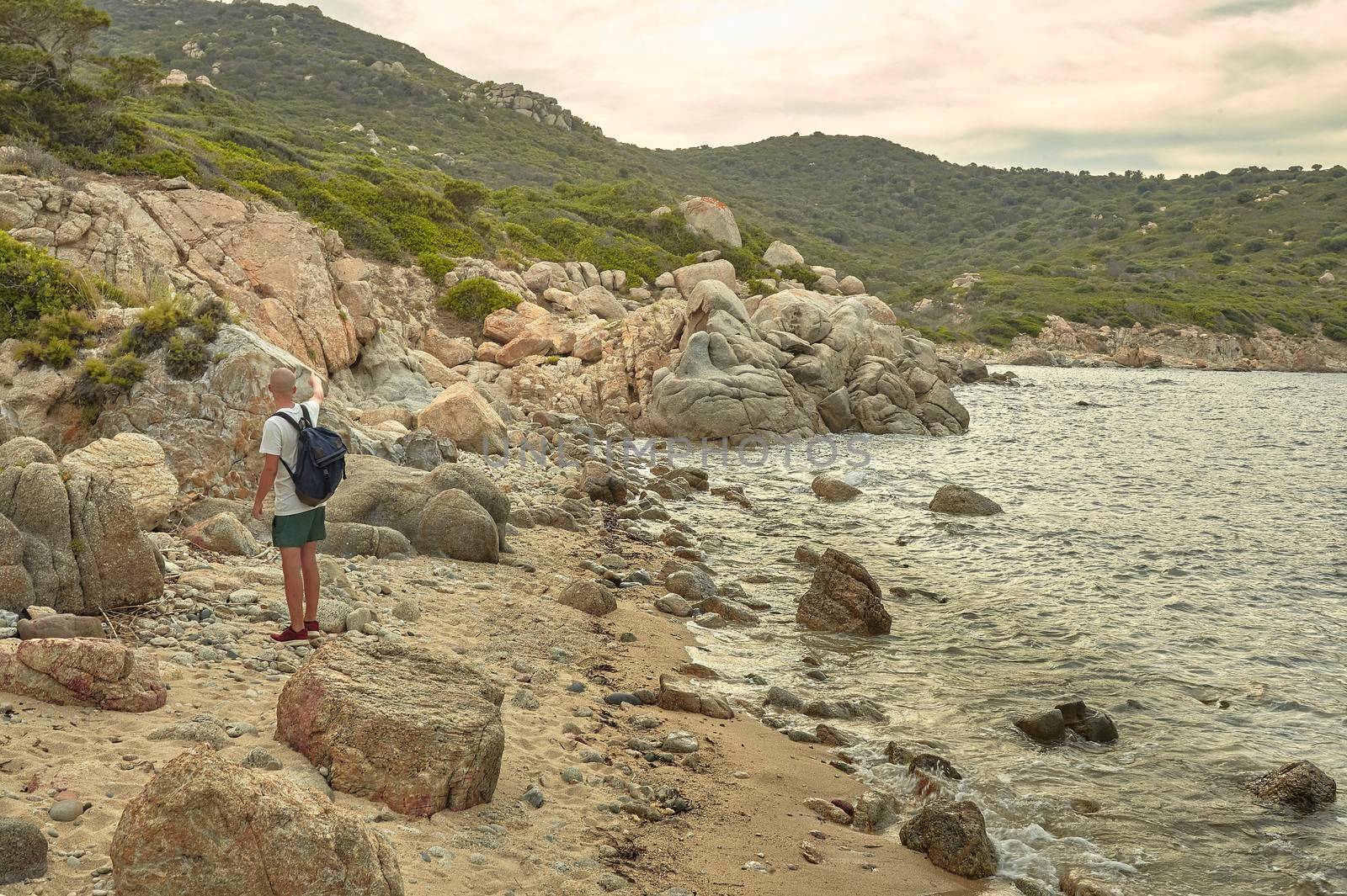 Young hiker is visiting a cliff typical of southern Sardinia during the sunset time.
