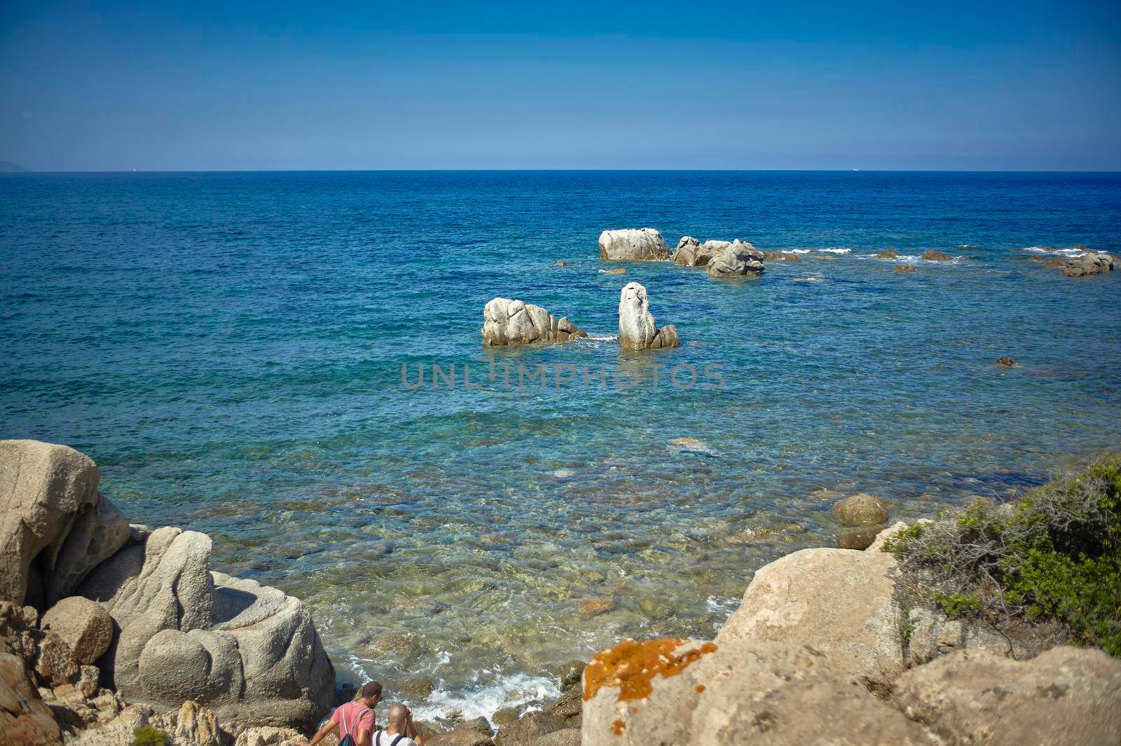 Postcard with blue sea and some pebbles that emerge from the water in the south of Sardinia.