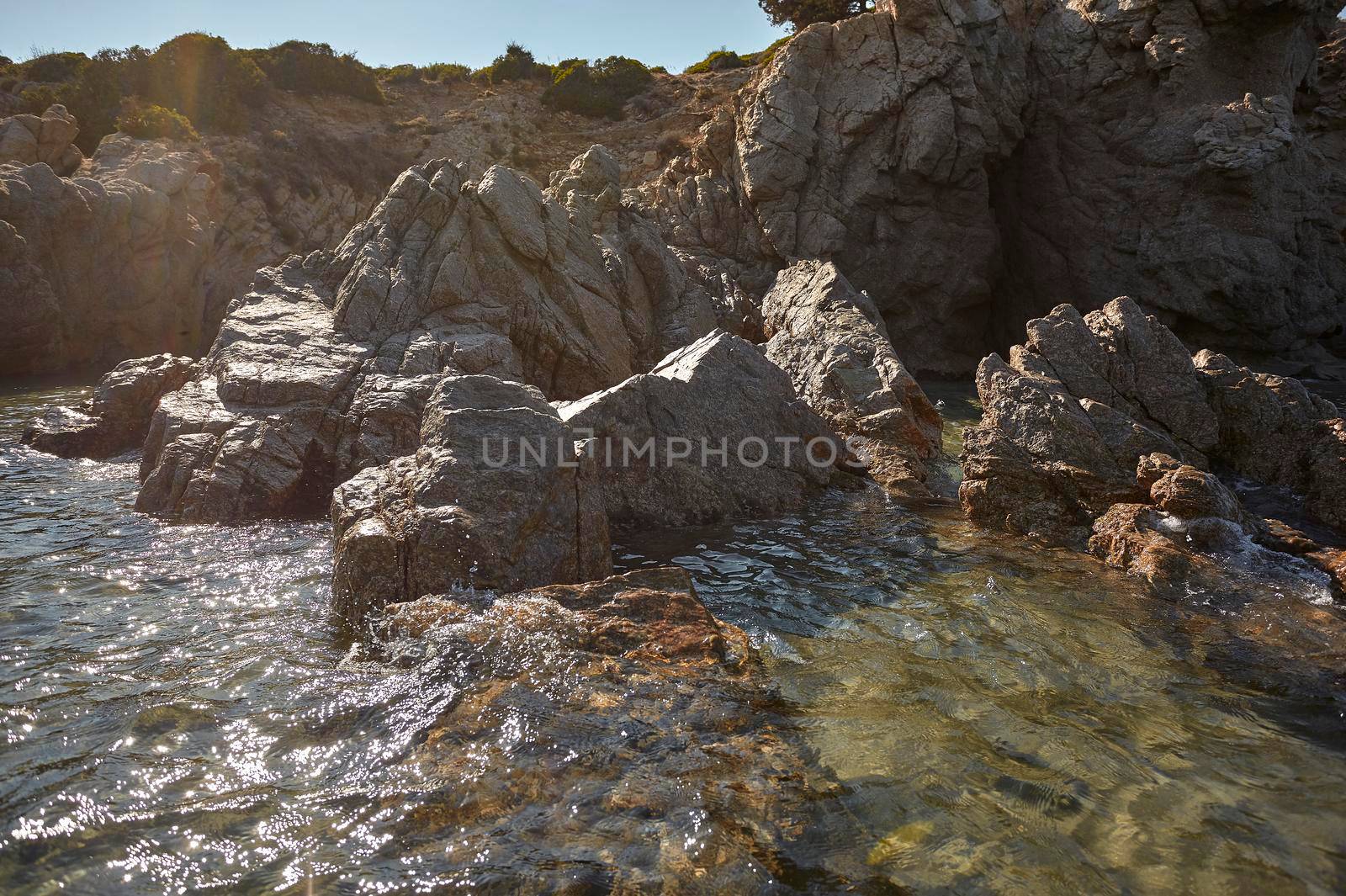 Rocks that emerge from the sea with transparent water in a Sardinian beach.