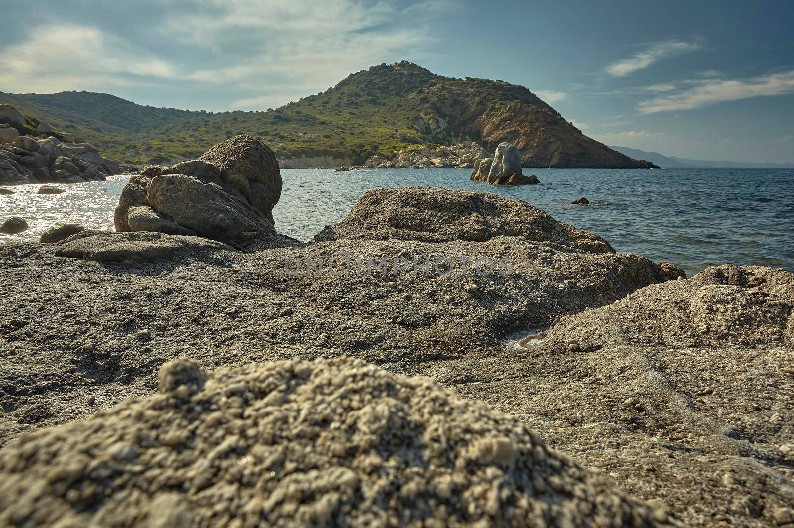 Background of a panorama including a rocky beach with the sea and the mountains full of Mediterranean vegetation in the background.