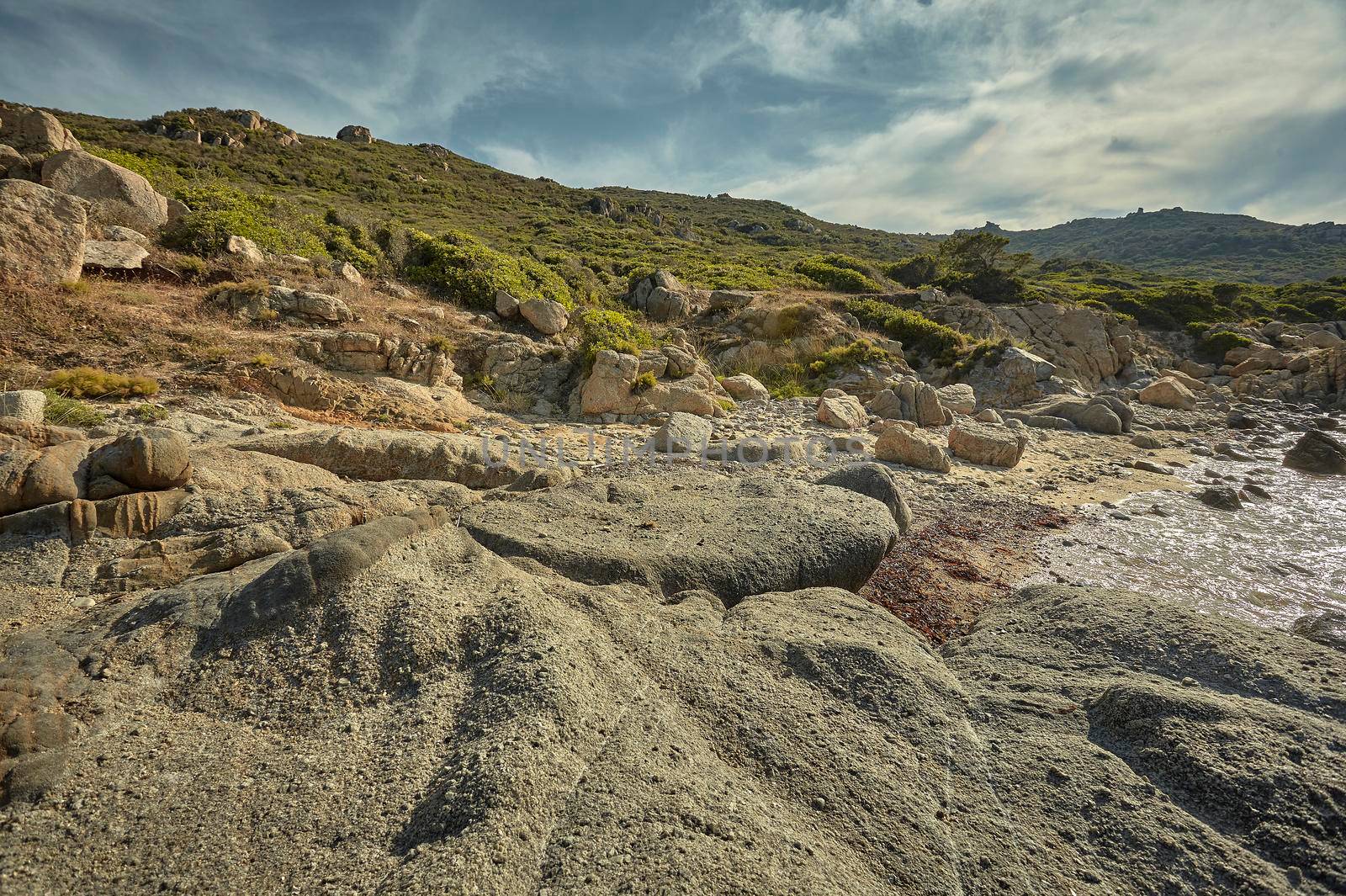 Background with a typical Mediterranean landscape formed by rocks, rocks and shrubbery on a beach in the summer.