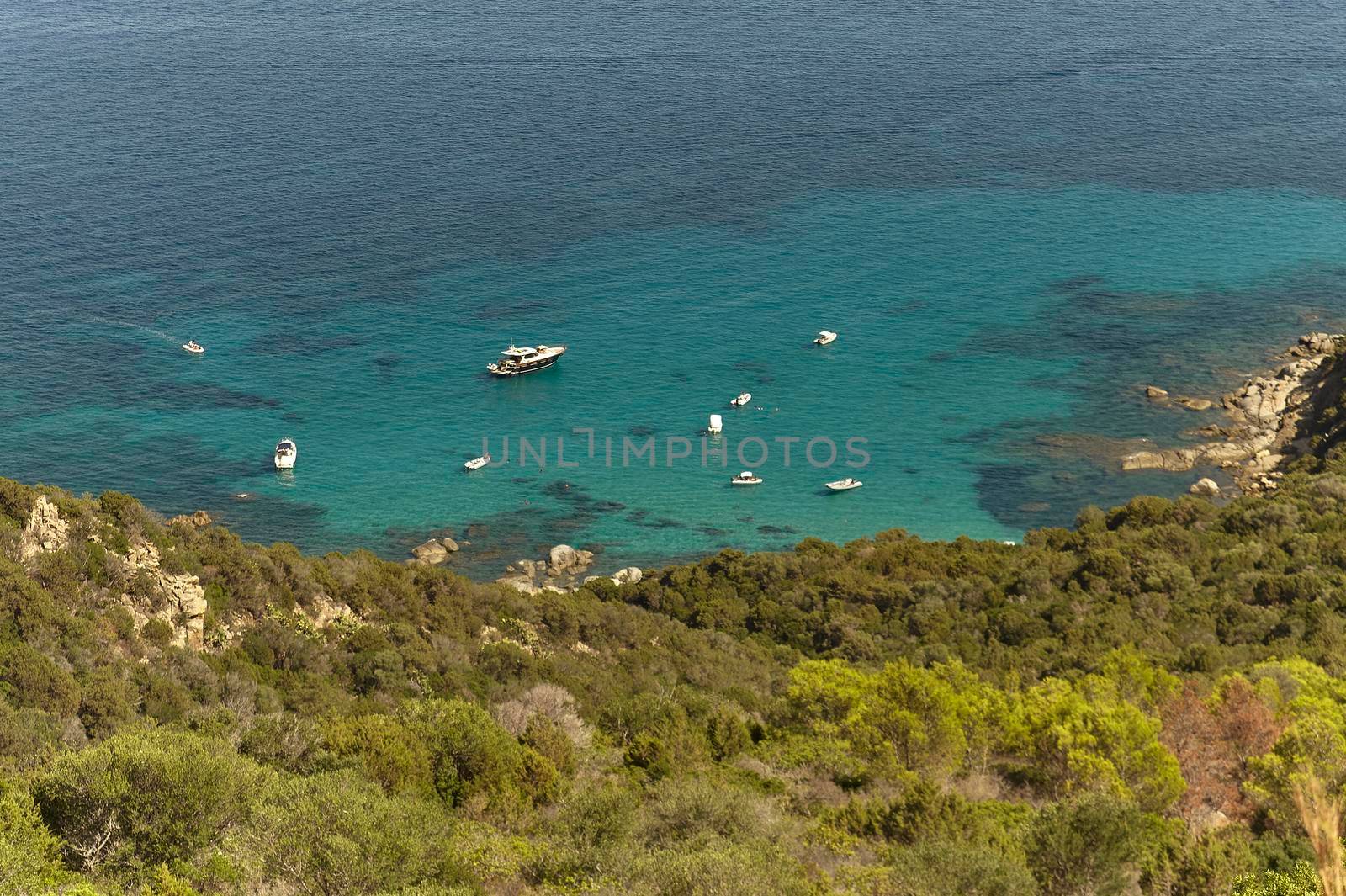 Top view of a portion of the coast facing the island of Serpentara in the south of Sardinia with some rubber boats used by tourists to visit this wonderful place.