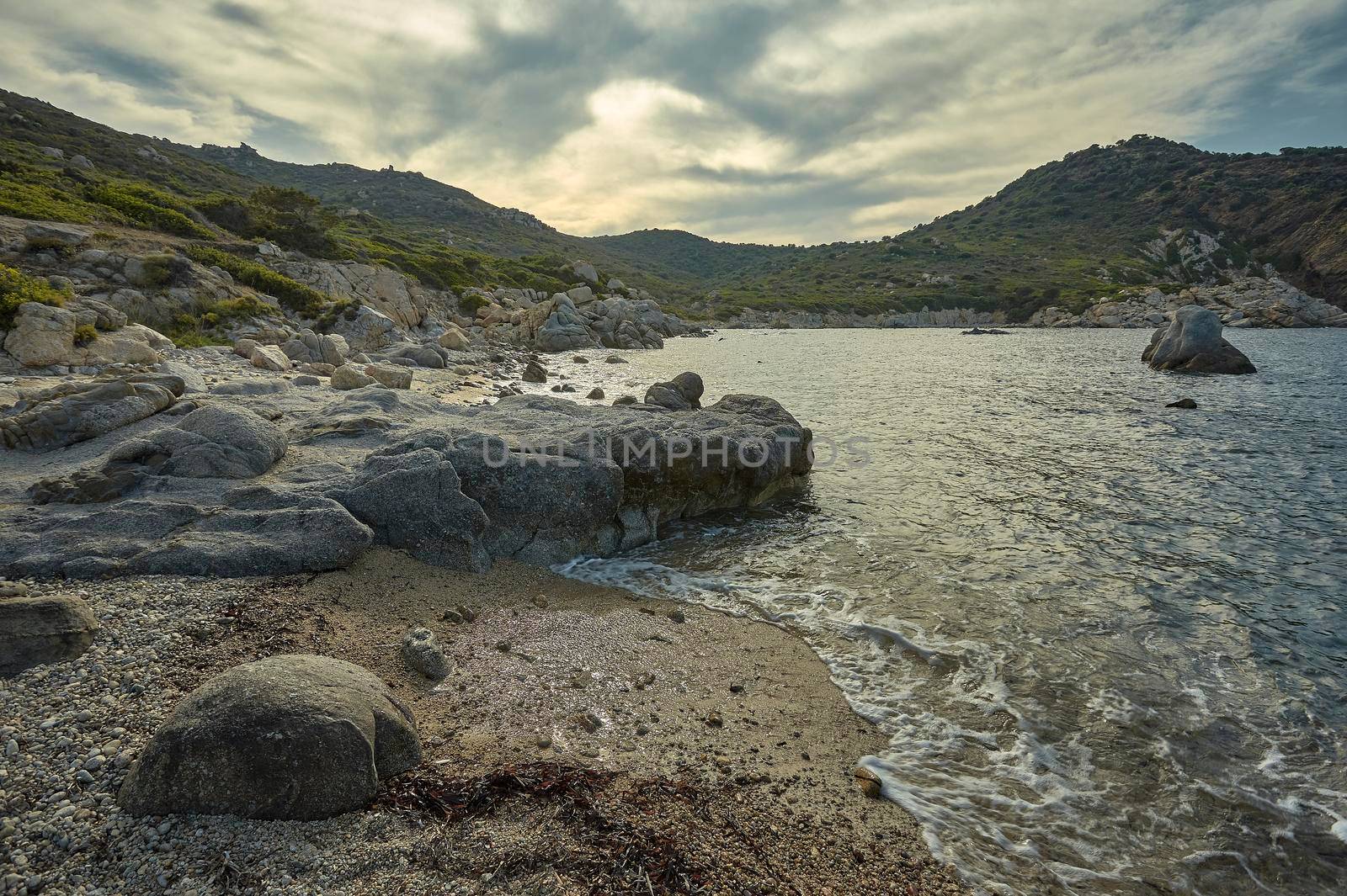 Wide-angle shot of a cliff typical of the landscapes of southern Sardinia with a wonderful beach at sunset.
