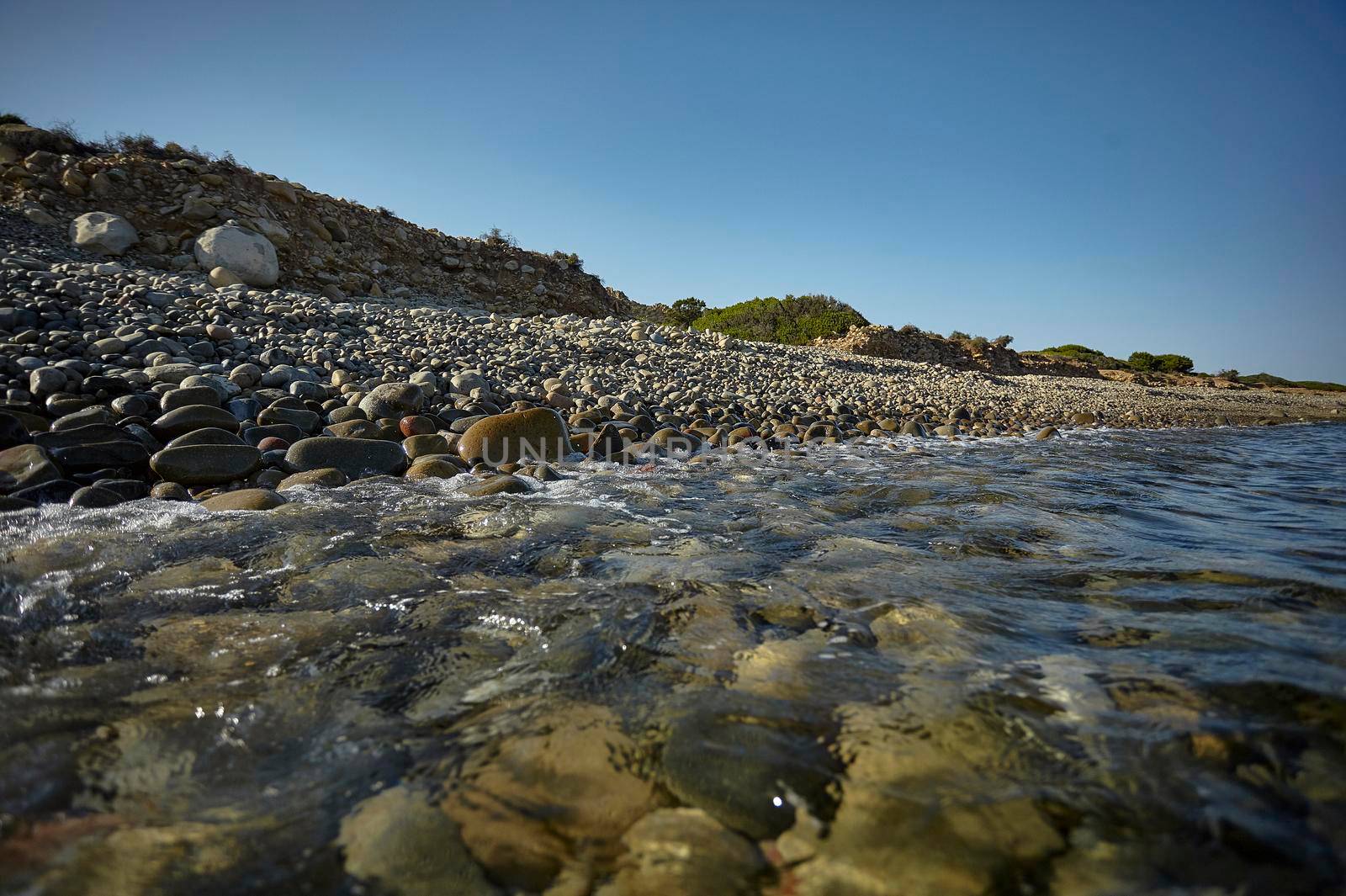 The crystalline water of the southern sea of Sardinia meets with the rocky beach breaking on the pebble stones.