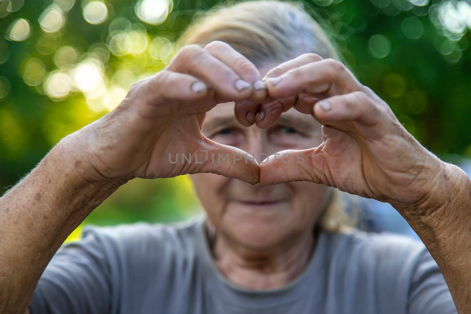 grandmother makes a heart with her hands. Selective focus. People.