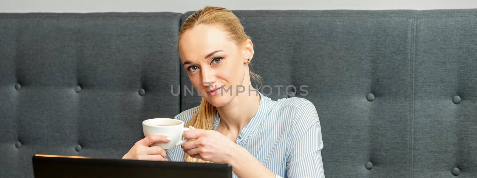 Portrait of a young businesswoman using laptop sitting at the table with a cup of coffee in a cafe
