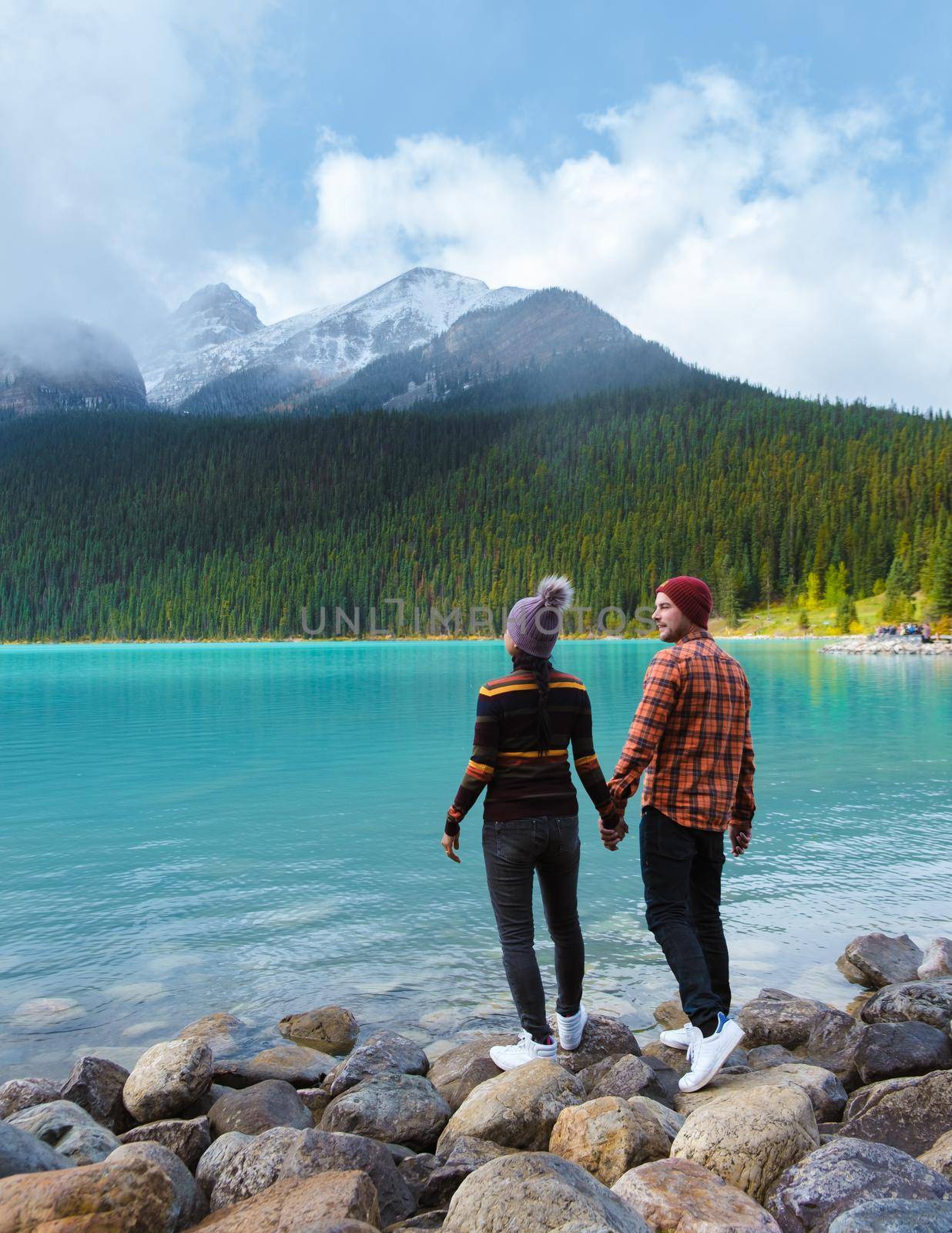 Lake Louise Banff national park, is a lake in the Canadian Rocky Mountains. A young couple of men and women standing by the lake during a cold day in Autumn in Canada