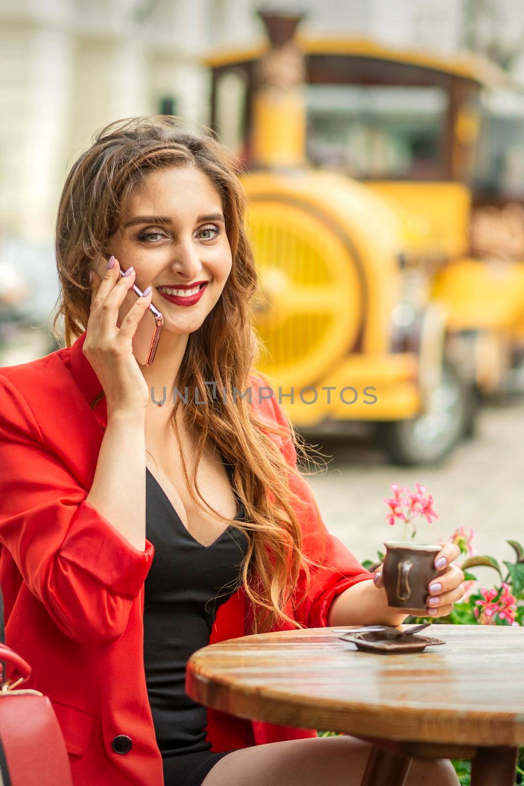 Beautiful young caucasian tourist woman talks on the phone sitting at the table in the street cafe in a European city