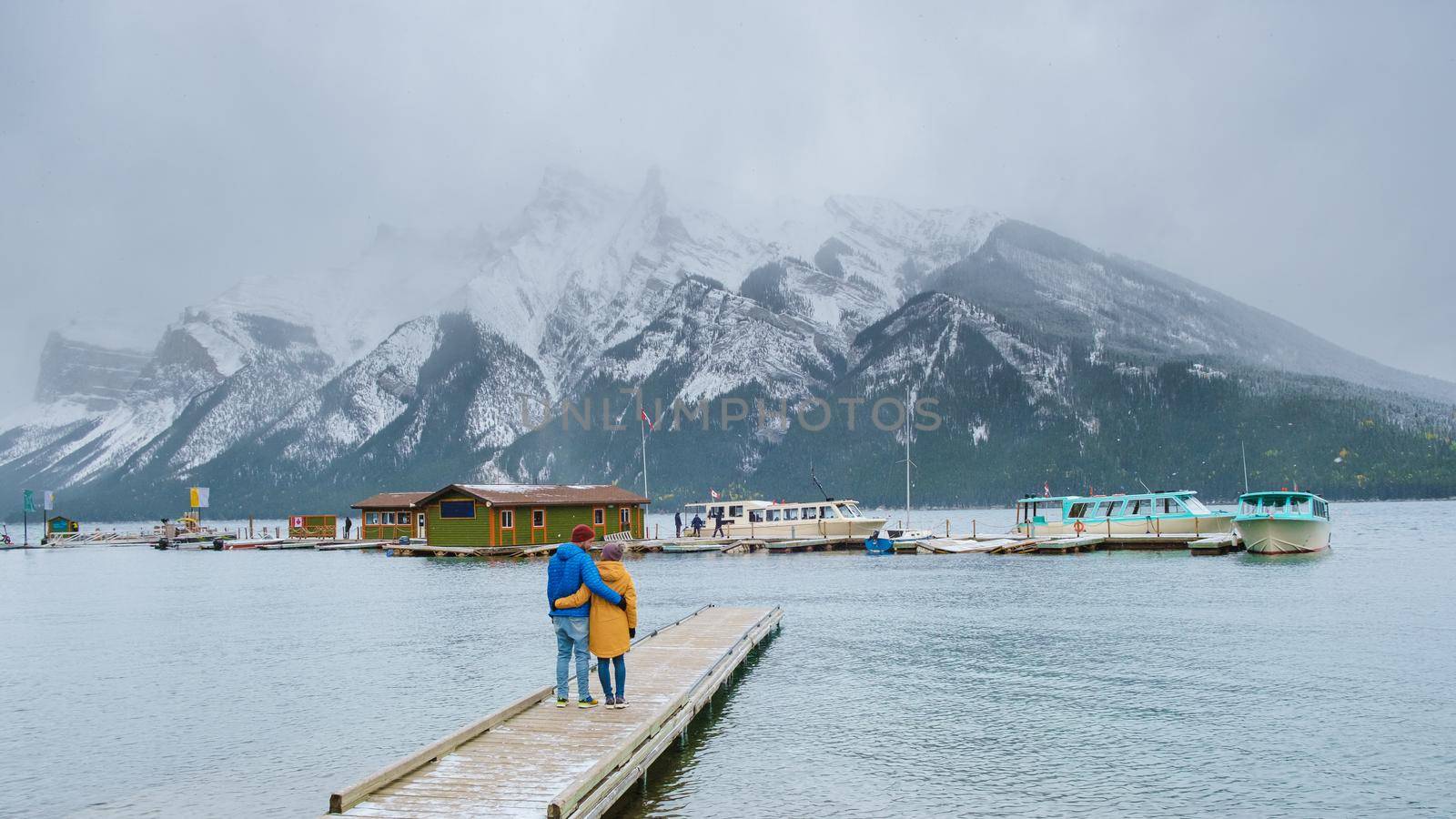 Minnewanka lake in the Canadian Rockies in Banff Alberta Canada with turquoise water, Lake Two Jack in the Rocky Mountains of Canada. a couple of men and women hiking by the lake during snow weather