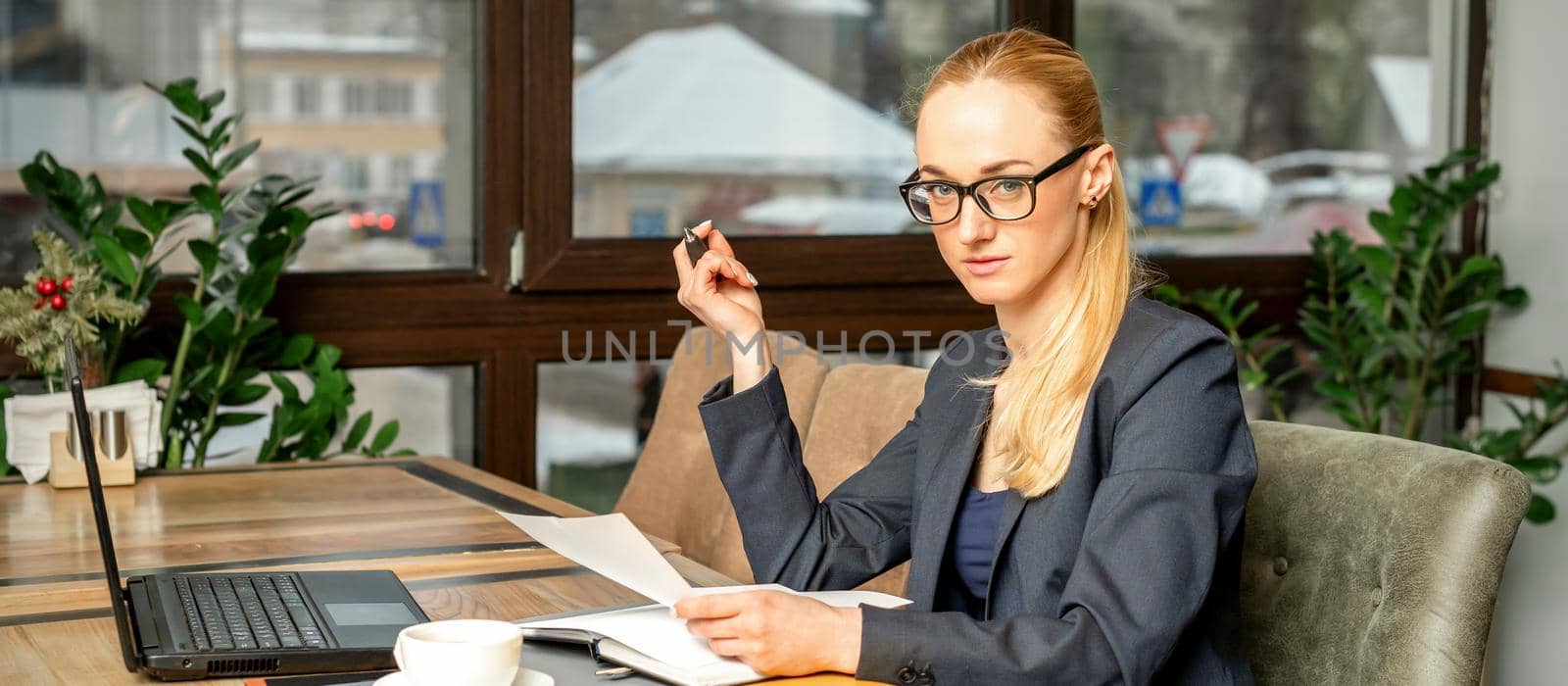 Beautiful young caucasian businesswoman working with documents in a cafe