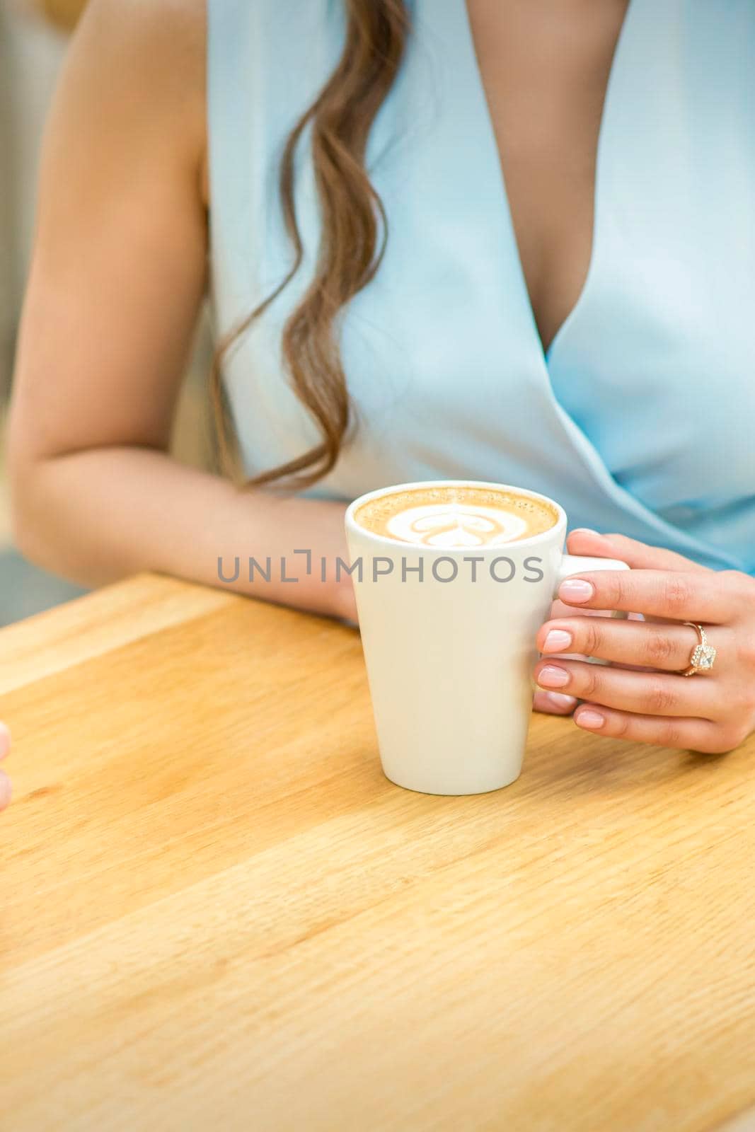 Female hands with cup of coffee on the background of a wooden table in a cafe