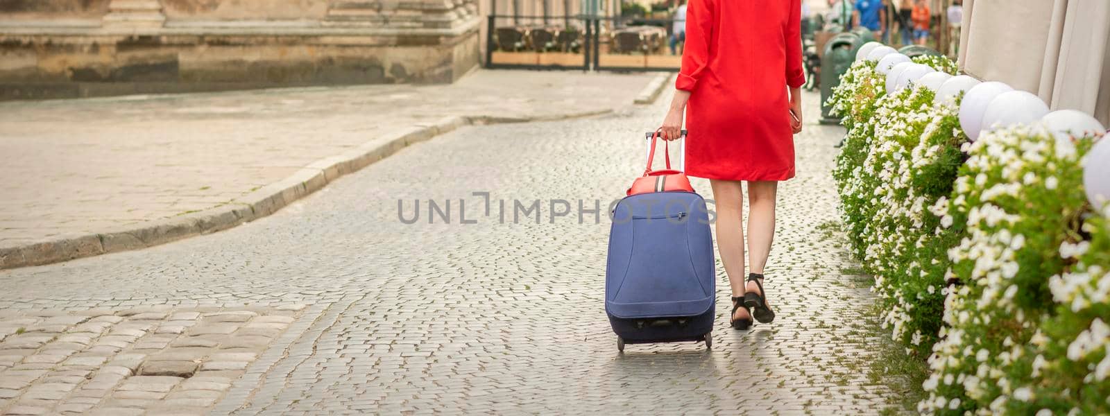 A young woman in a black hat with a suitcase walks on the European city street