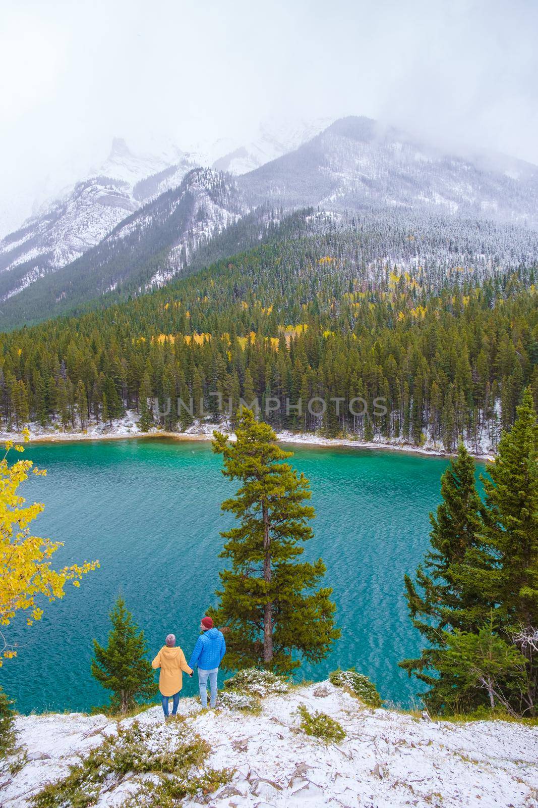 Minnewanka lake in the Canadian Rockies in Banff Alberta Canada with turquoise water, Lake Two Jack in the Rocky Mountains of Canada. a couple of men and women hiking by the lake during snow weather