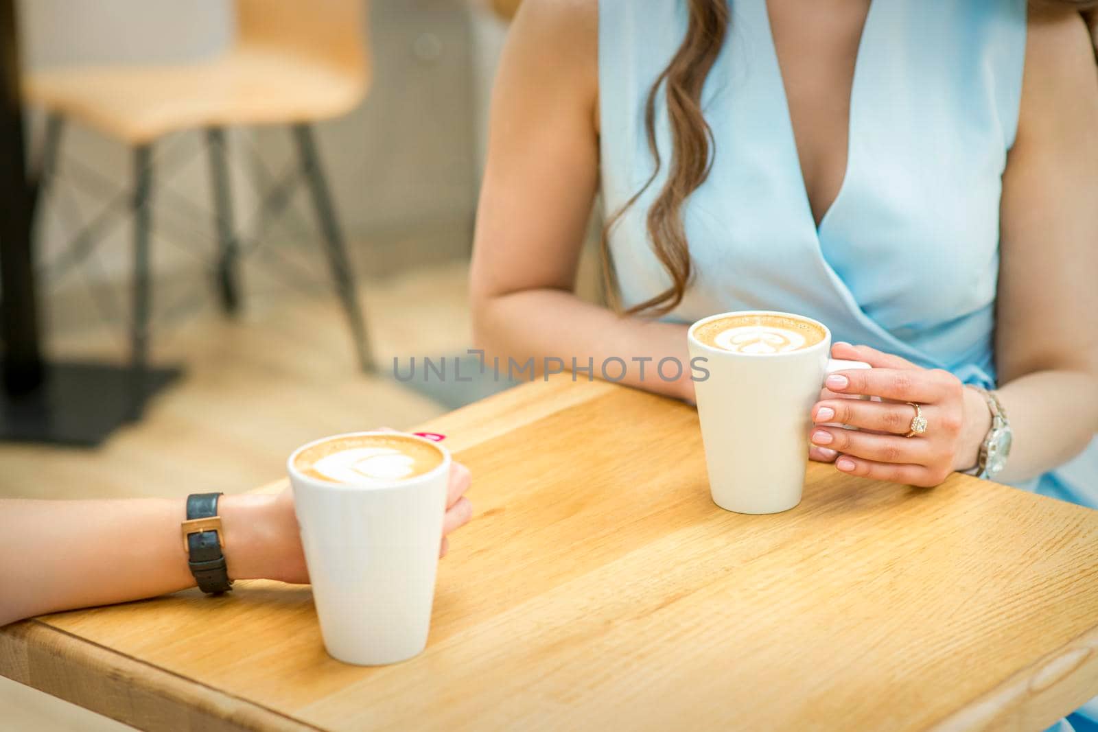 Female hands with cups of coffee on the background of a wooden table in a cafe