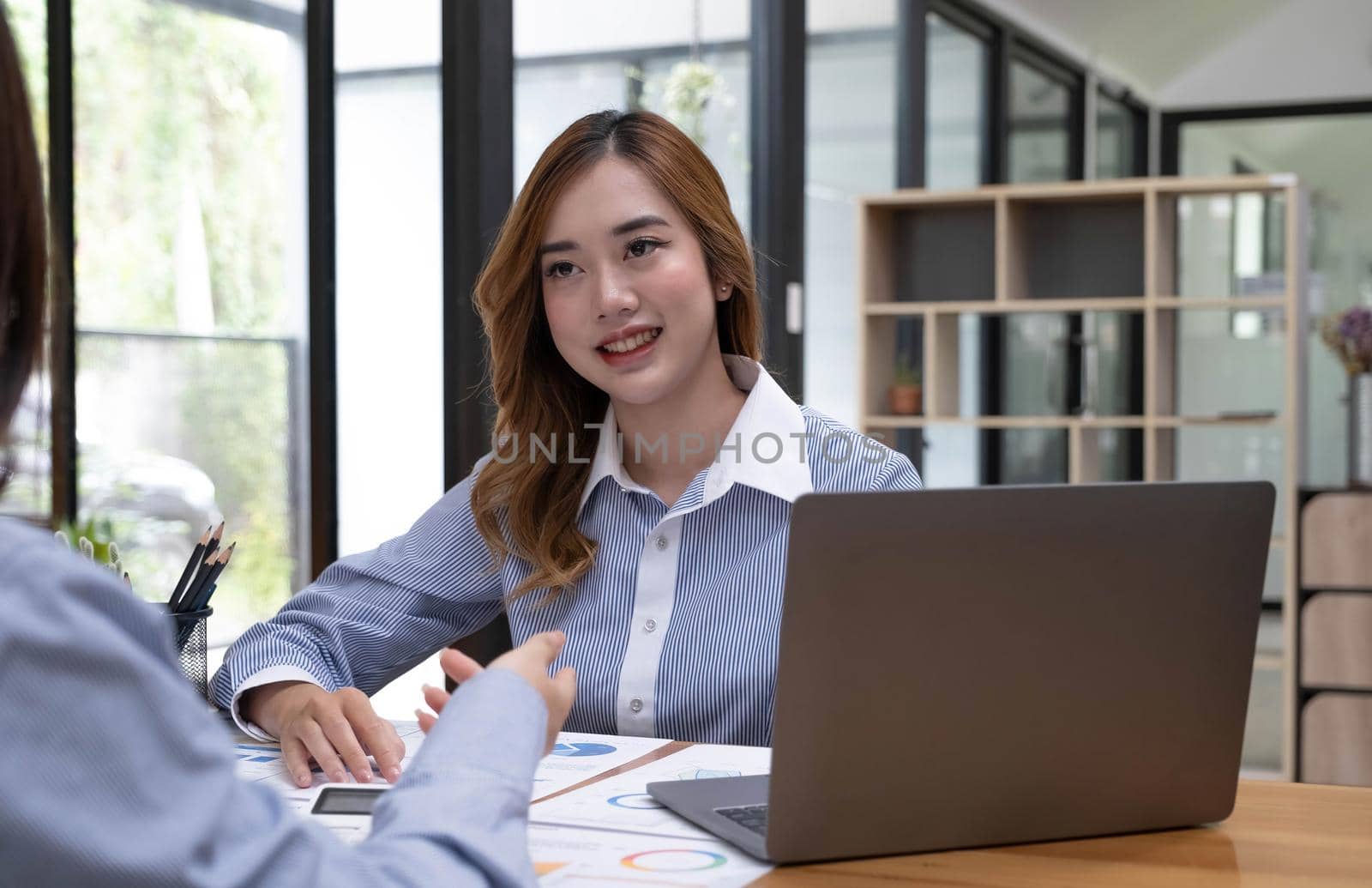 Two young Asian businesswoman discuss investment project working and planning strategy. Business people talking together with laptop computer at office. by wichayada