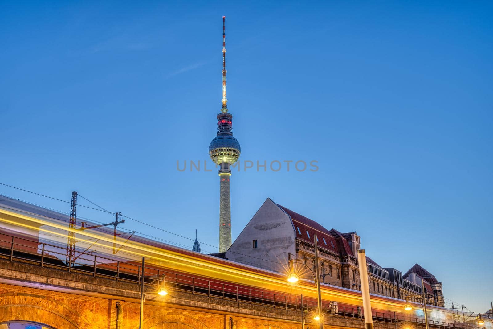 The famous Television Tower in Berlin at dusk with a motion blurred commuter train