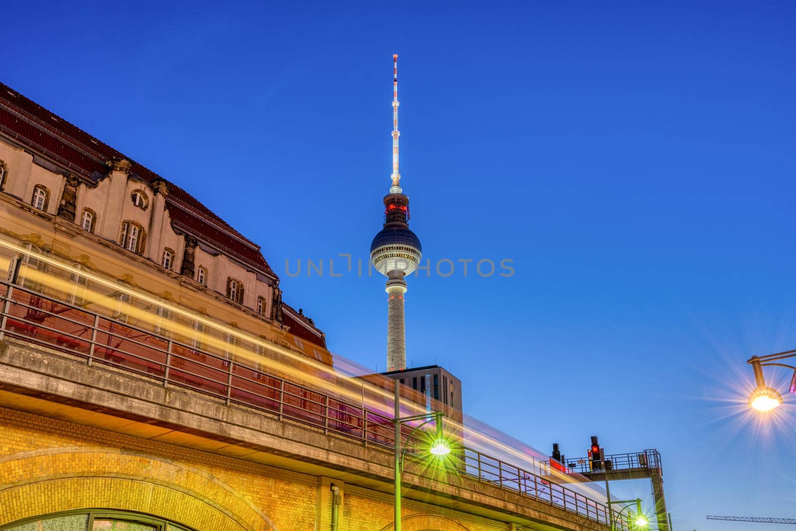 The iconic TV Tower in Berlin at dusk with a motion blurred commuter train